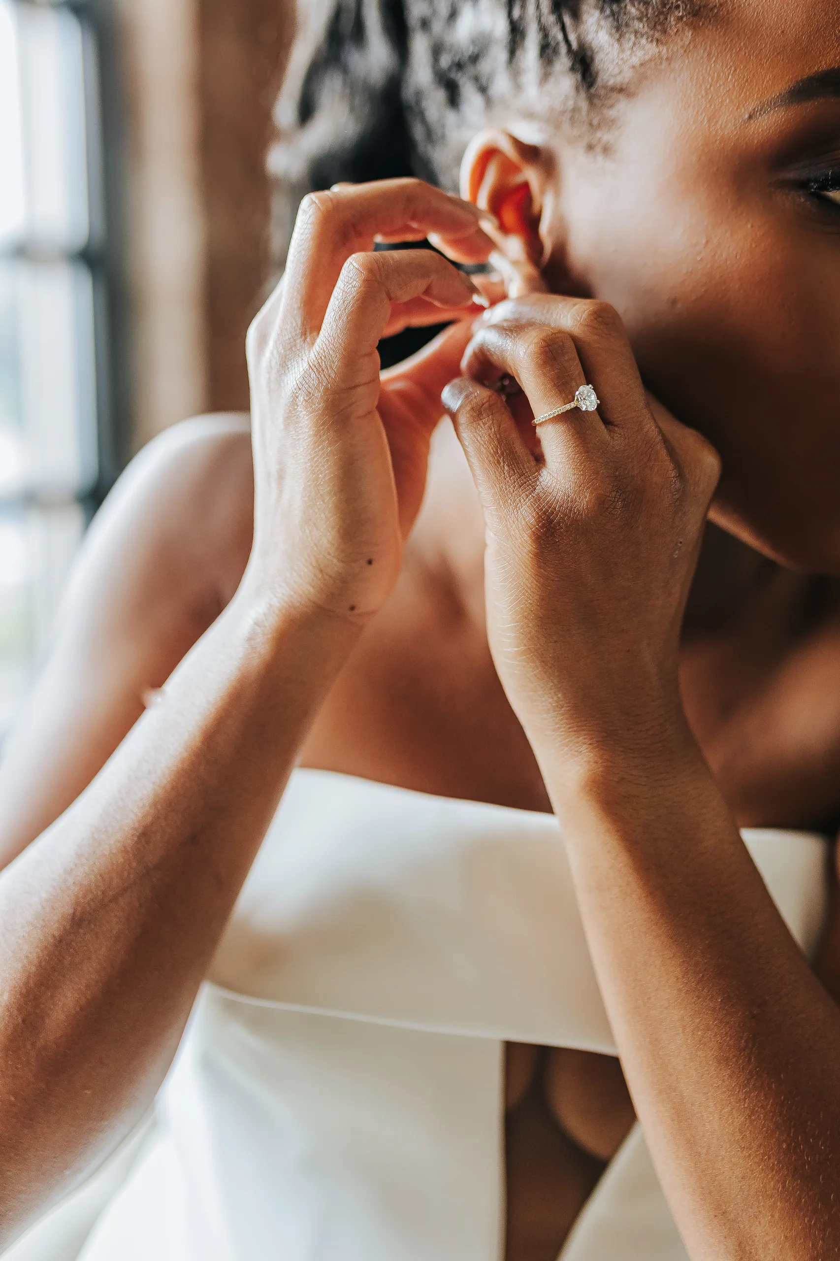 Bridal Portraits: the bride putting in her earrings, her ring on, at their wedding at Terminus 330 in Atlanta, GA