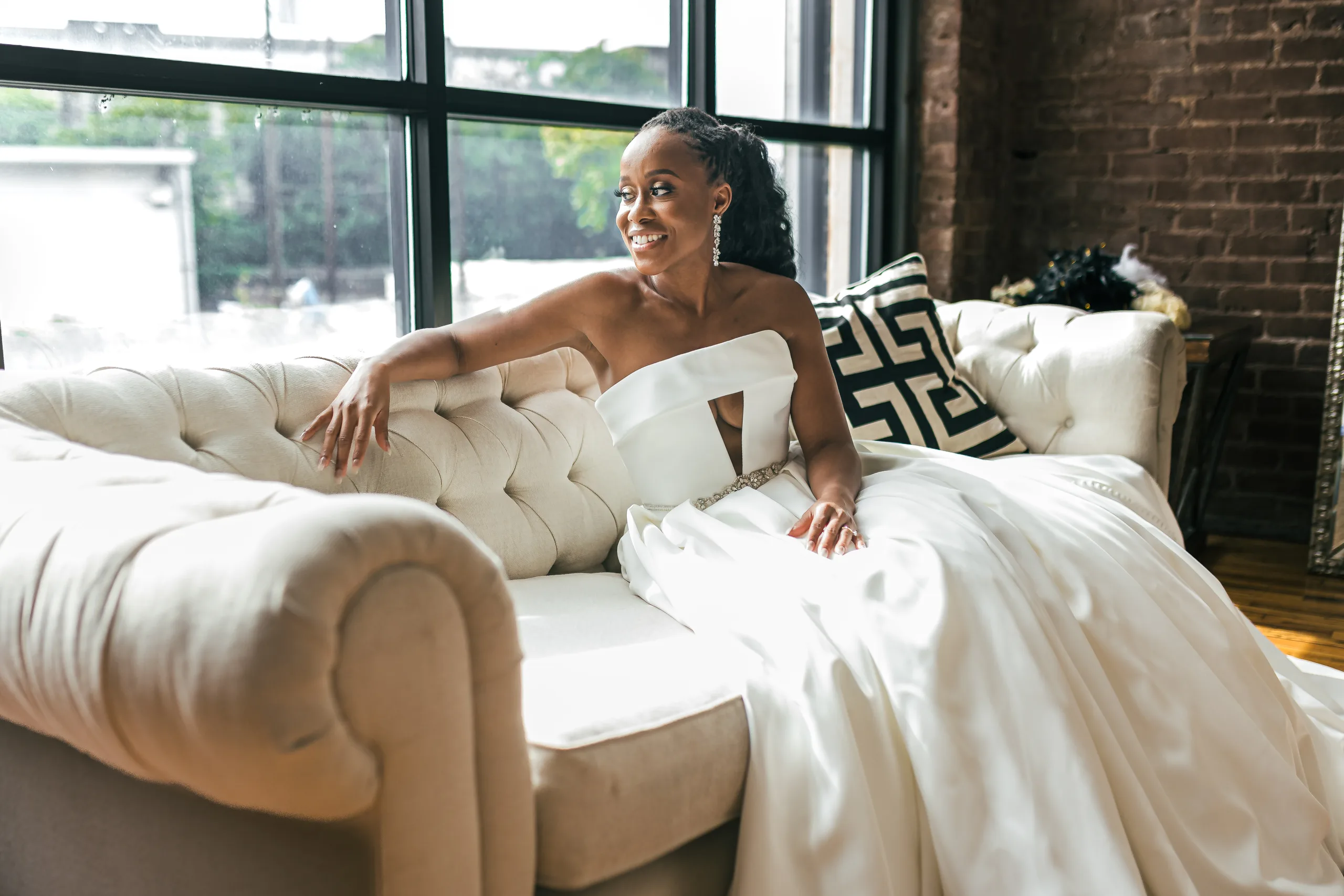 Bridal Portraits: the bride on a tufted sofa by the big windows, at their wedding at Terminus 330 in Atlanta, GA