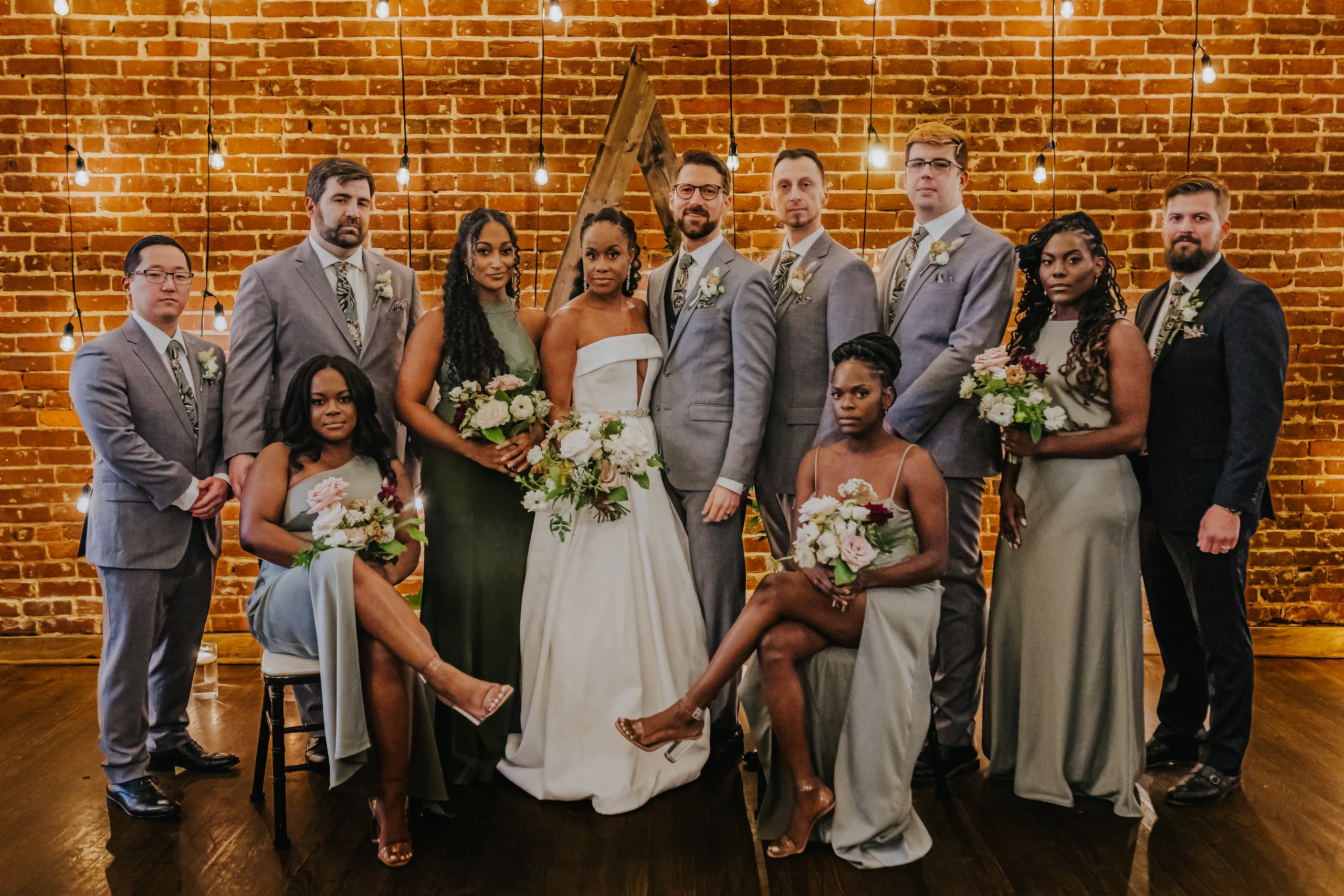 Wedding Party: the full wedding party in front of the brick wall and arch, at their wedding at Terminus 330 in Atlanta, GA