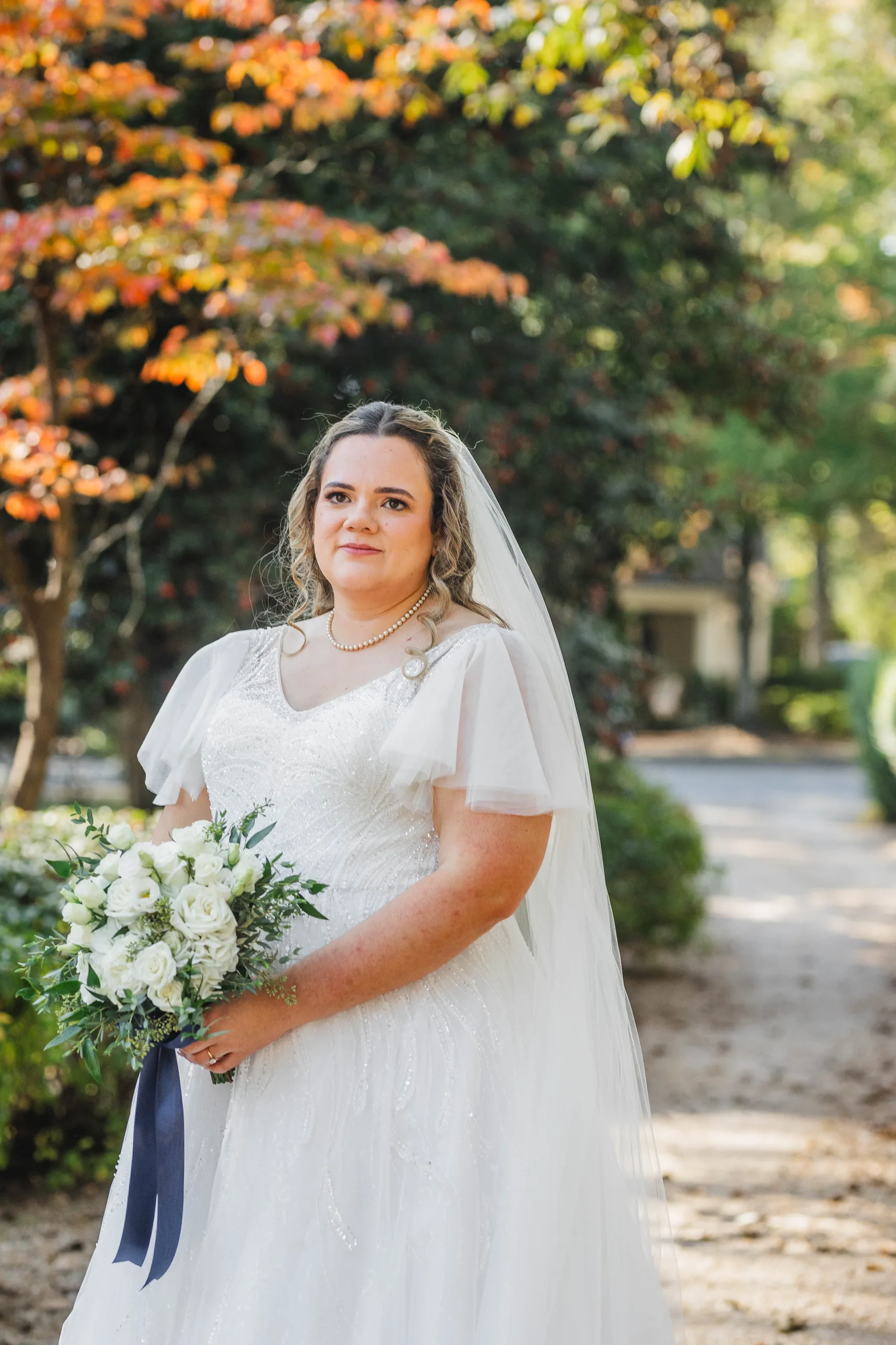 Bridal Portraits: the bride under an orange maple with her bouquet, at their wedding at Naylor Hall in Roswell, GA