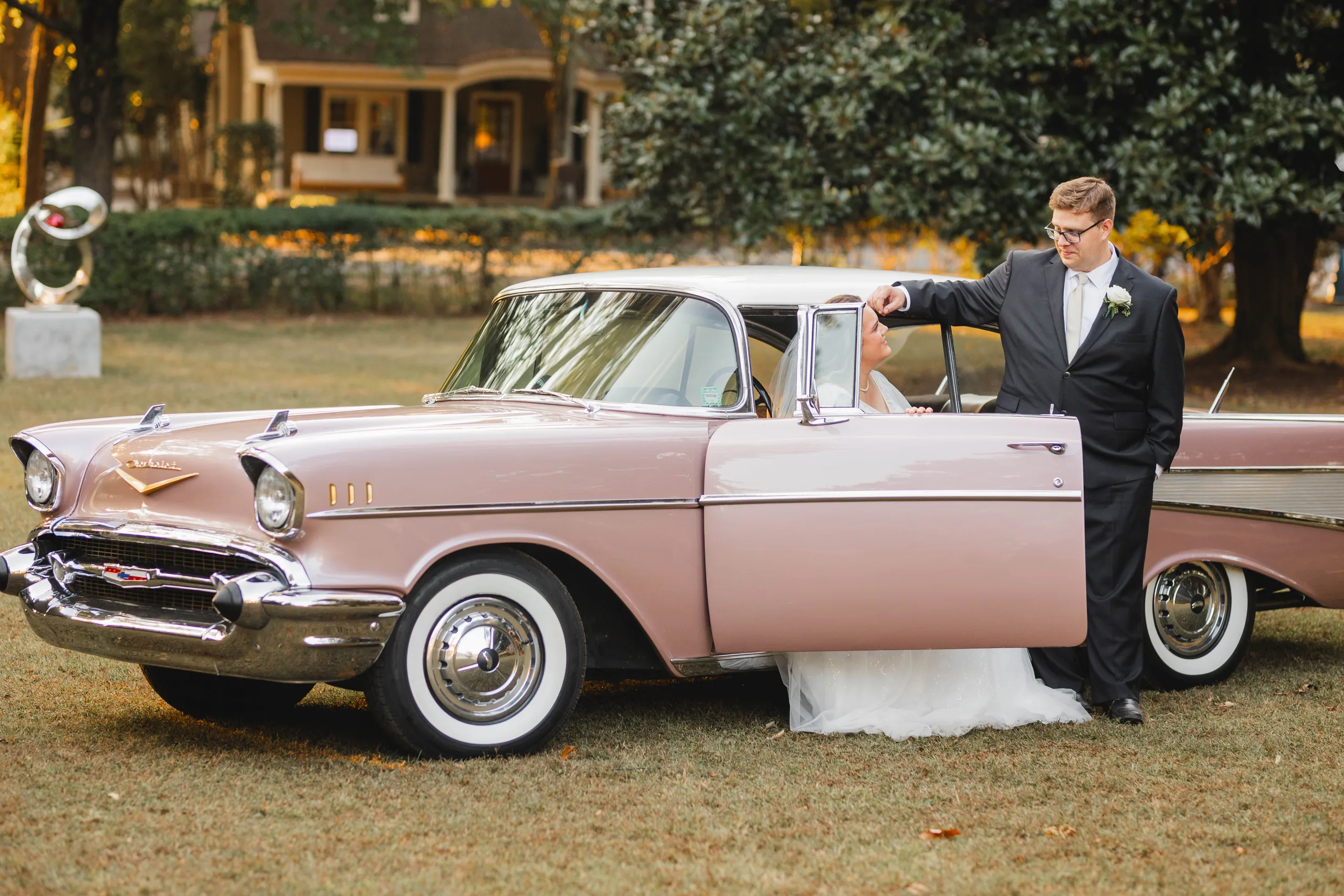 Wedding Formals: the groom holding the door of the pink Chevrolet for her, at their wedding at Naylor Hall in Roswell, GA