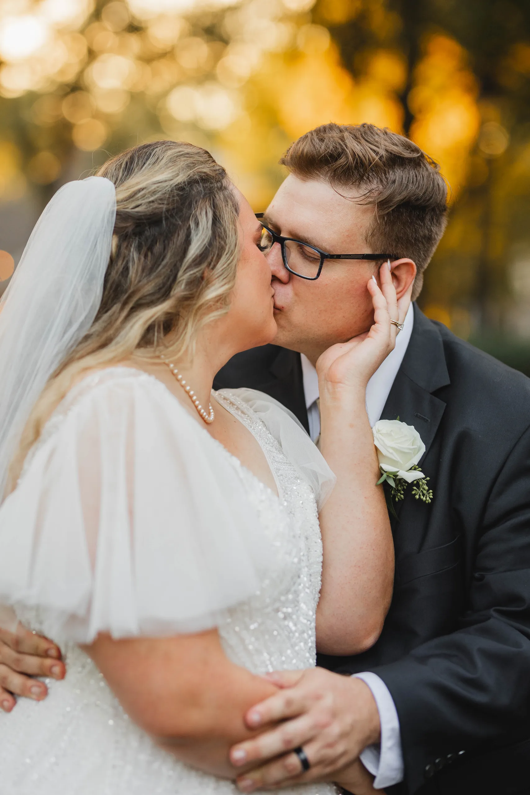 Wedding Formals: a kiss, her hand on his cheek, fall color behind them, at their wedding at Naylor Hall in Roswell, GA