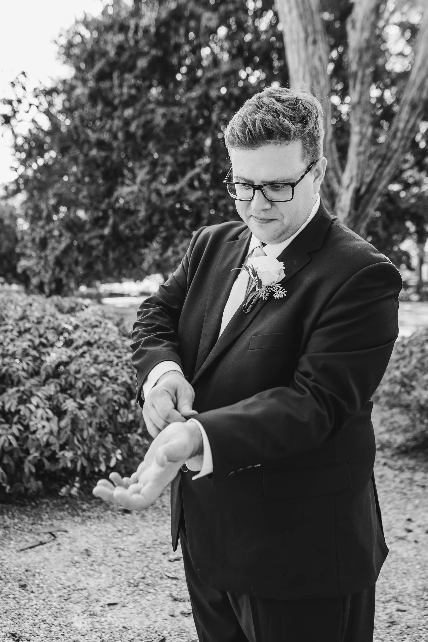 Wedding Formals: the groom fixing his cuff, in black and white, at their wedding at Naylor Hall in Roswell, GA
