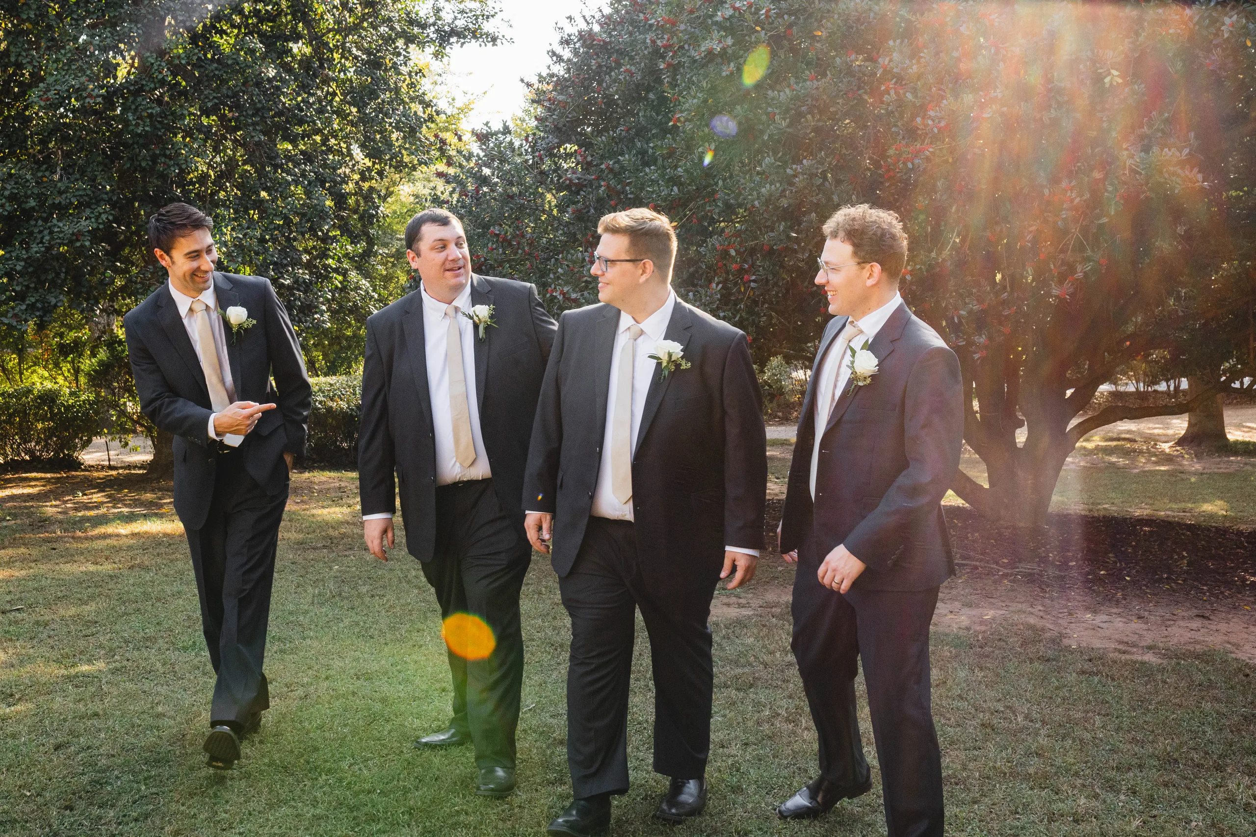Wedding Party: the groom and his groomsmen walking together in the sun, at their wedding at Naylor Hall in Roswell, GA