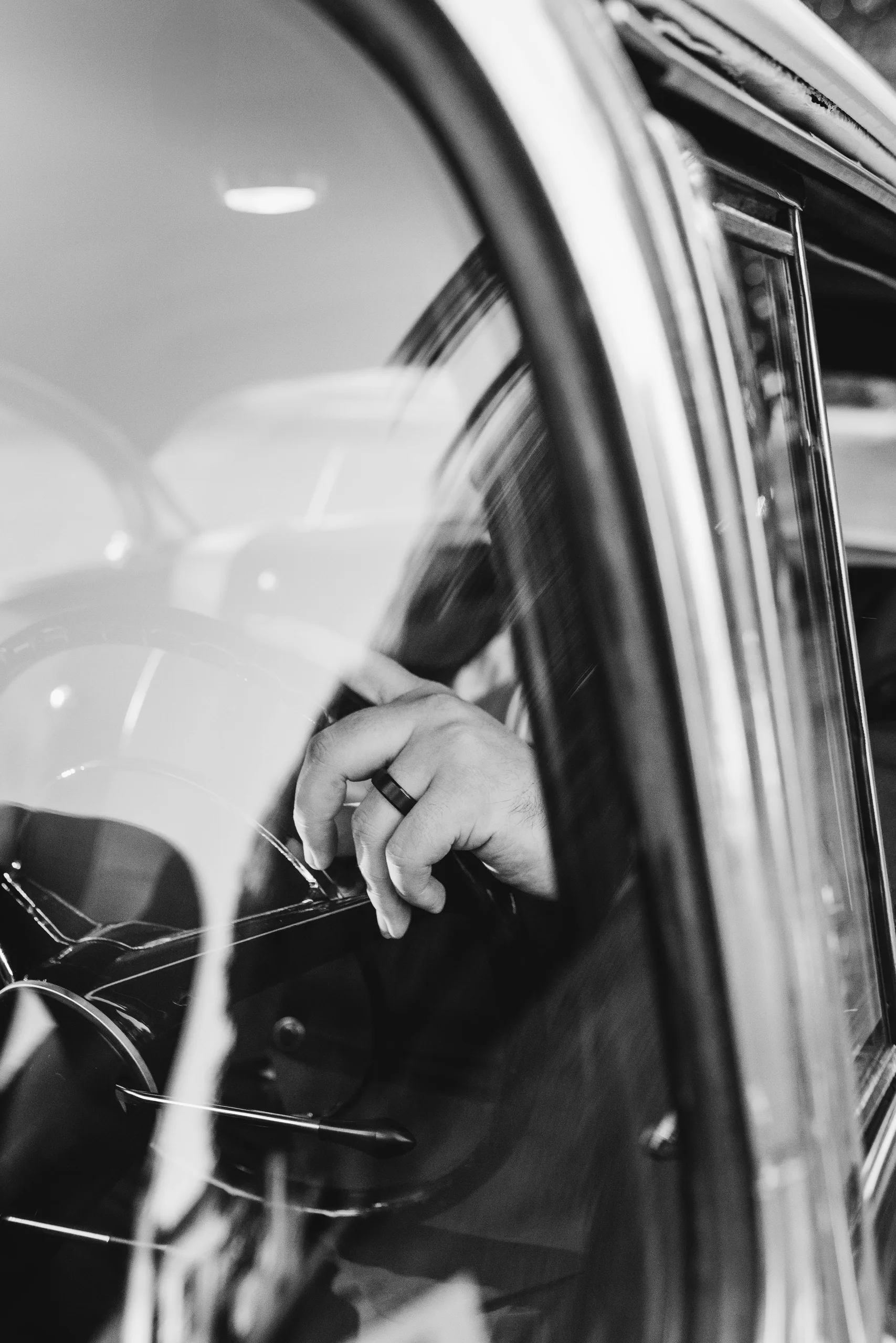 Wedding Formals: his hand on the steering wheel through the car window, in black and white, at their wedding at Naylor Hall in Roswell, GA