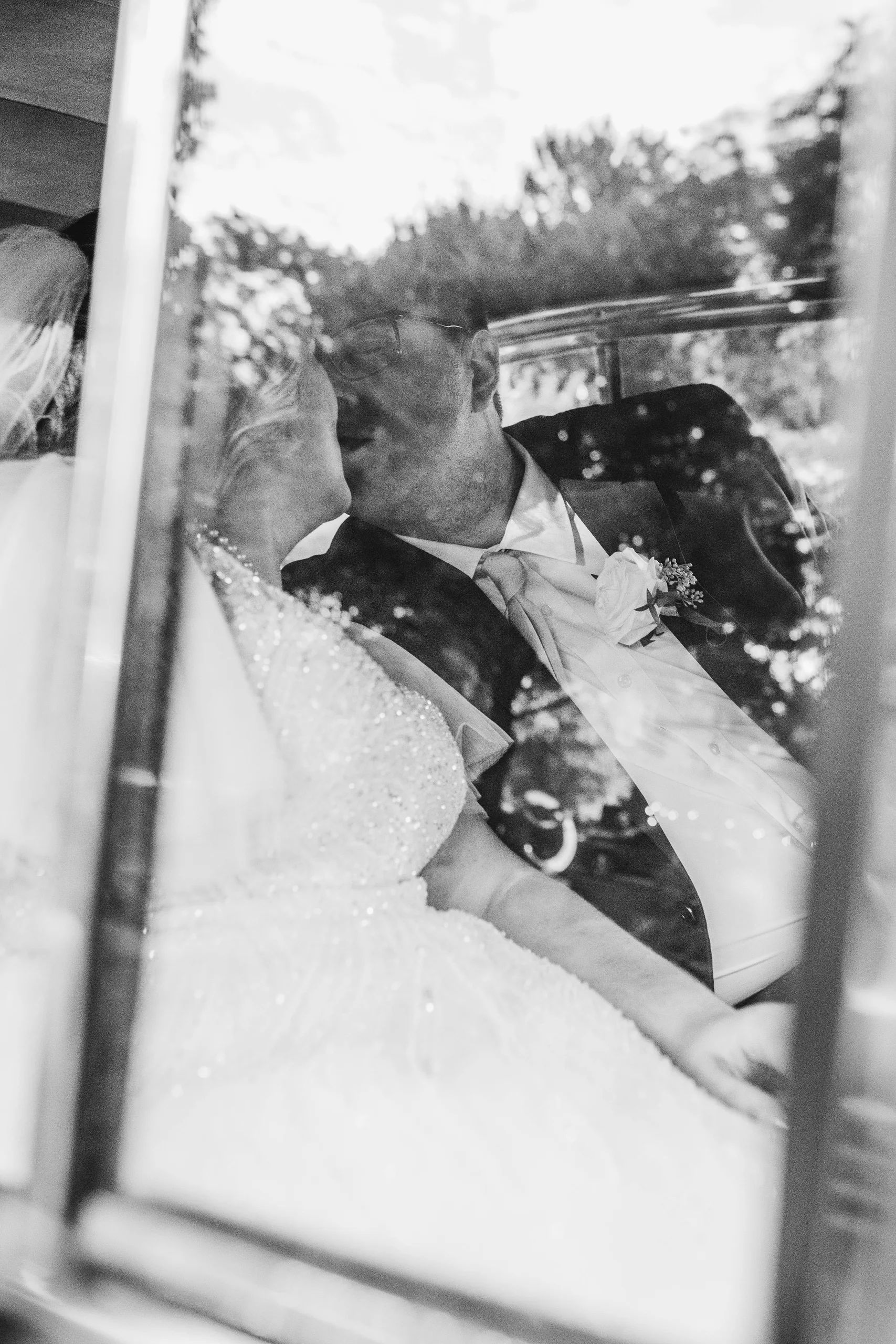 Wedding Formals: a kiss inside the car seen through the window, in black and white, at their wedding at Naylor Hall in Roswell, GA