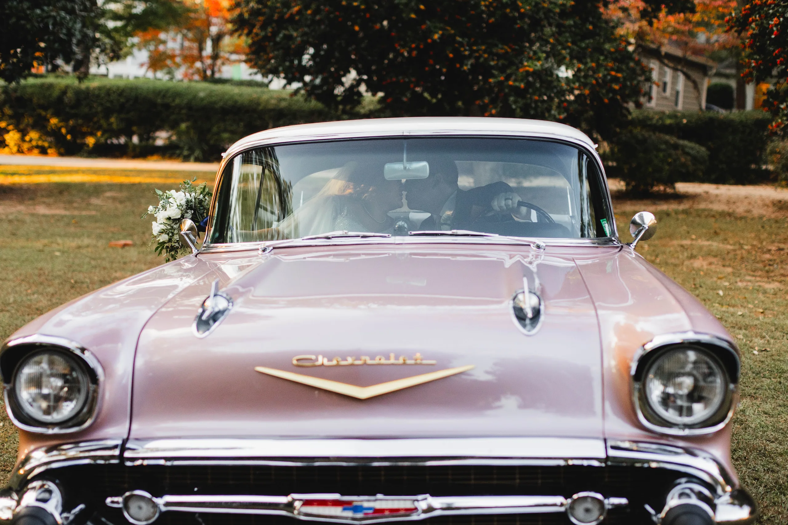Wedding Formals: the Chevrolet hood and chrome, the two of them kissing behind the windshield, at their wedding at Naylor Hall in Roswell, GA