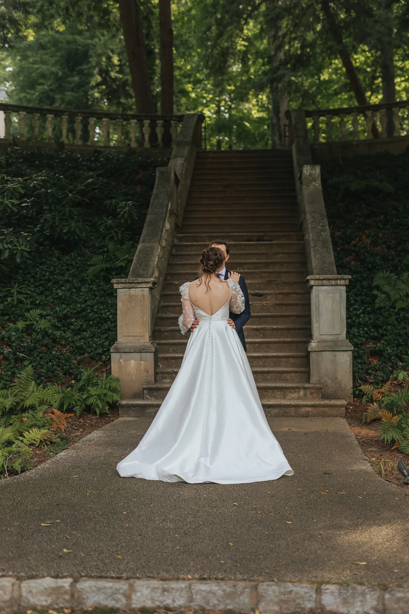 Wedding Formals: an embrace at the bottom of the grand staircase, on their wedding day at Cator Woolford Gardens in Atlanta, GA