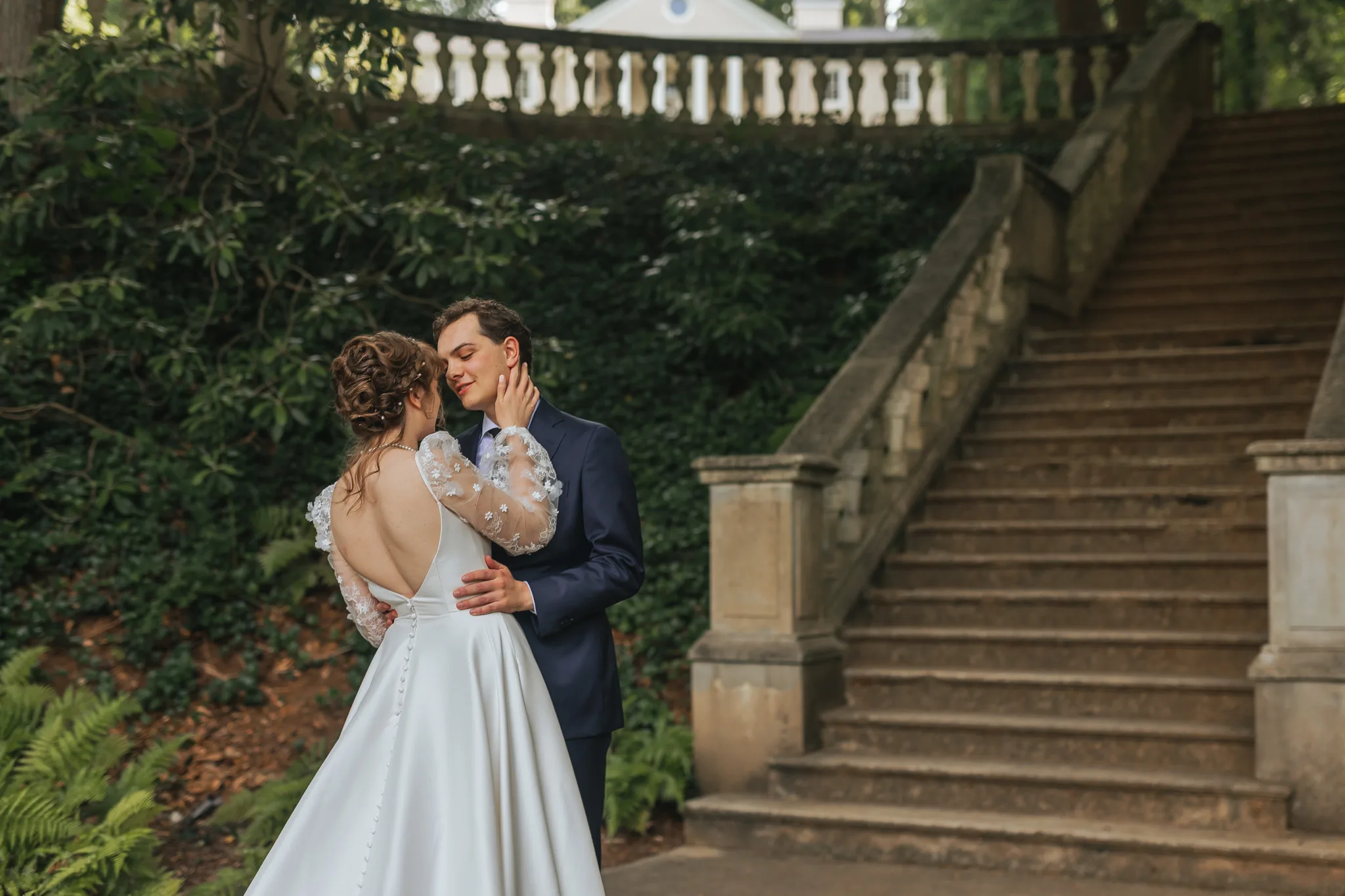 Wedding Formals: her hand on his face in front of the staircase, on their wedding day at Cator Woolford Gardens in Atlanta, GA