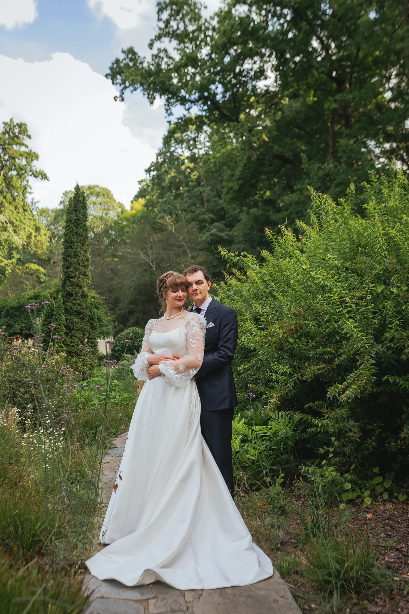 Wedding Formals: the groom holding her from behind on a garden path, on their wedding day at Cator Woolford Gardens in Atlanta, GA