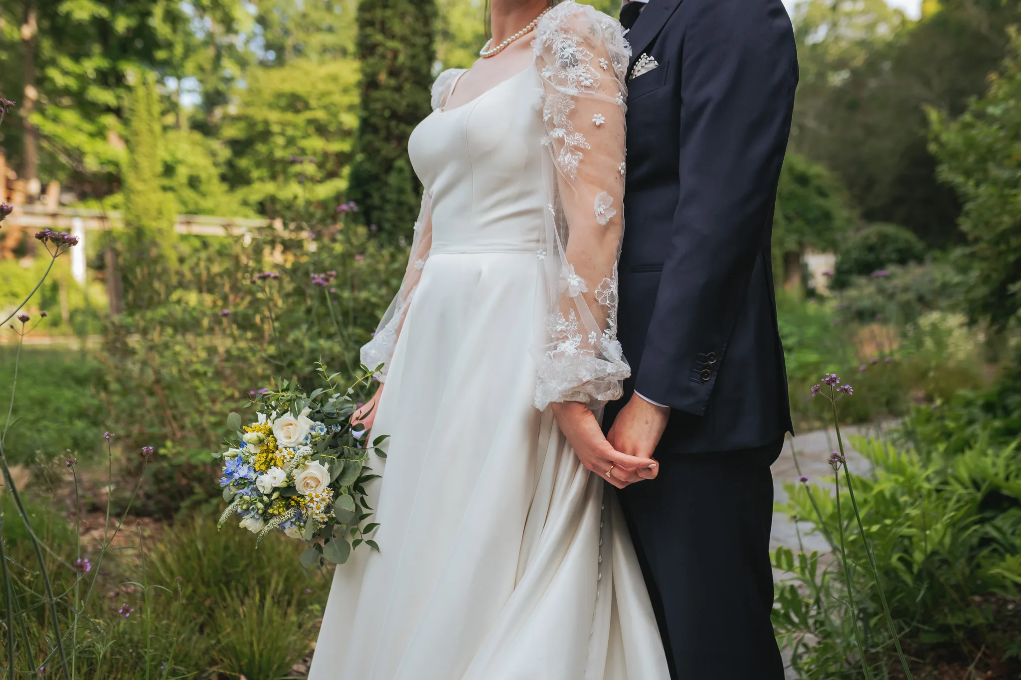 Wedding Formals: holding hands, her bouquet at her side, on their wedding day at Cator Woolford Gardens in Atlanta, GA