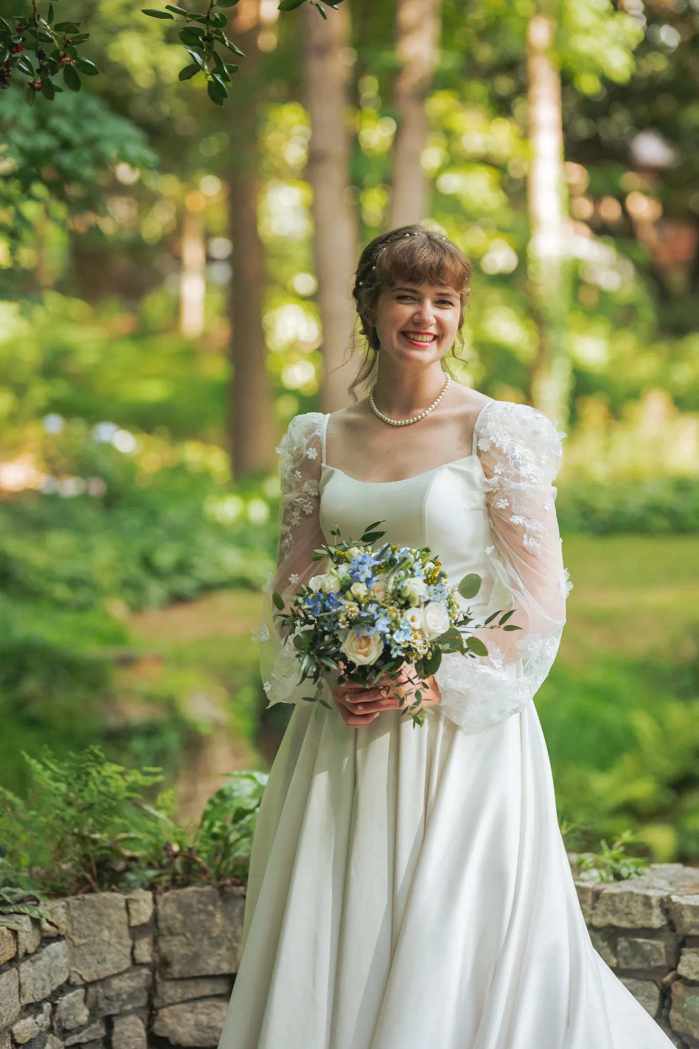 Bridal Portraits: the bride with her bouquet by a stone wall, on their wedding day at Cator Woolford Gardens in Atlanta, GA