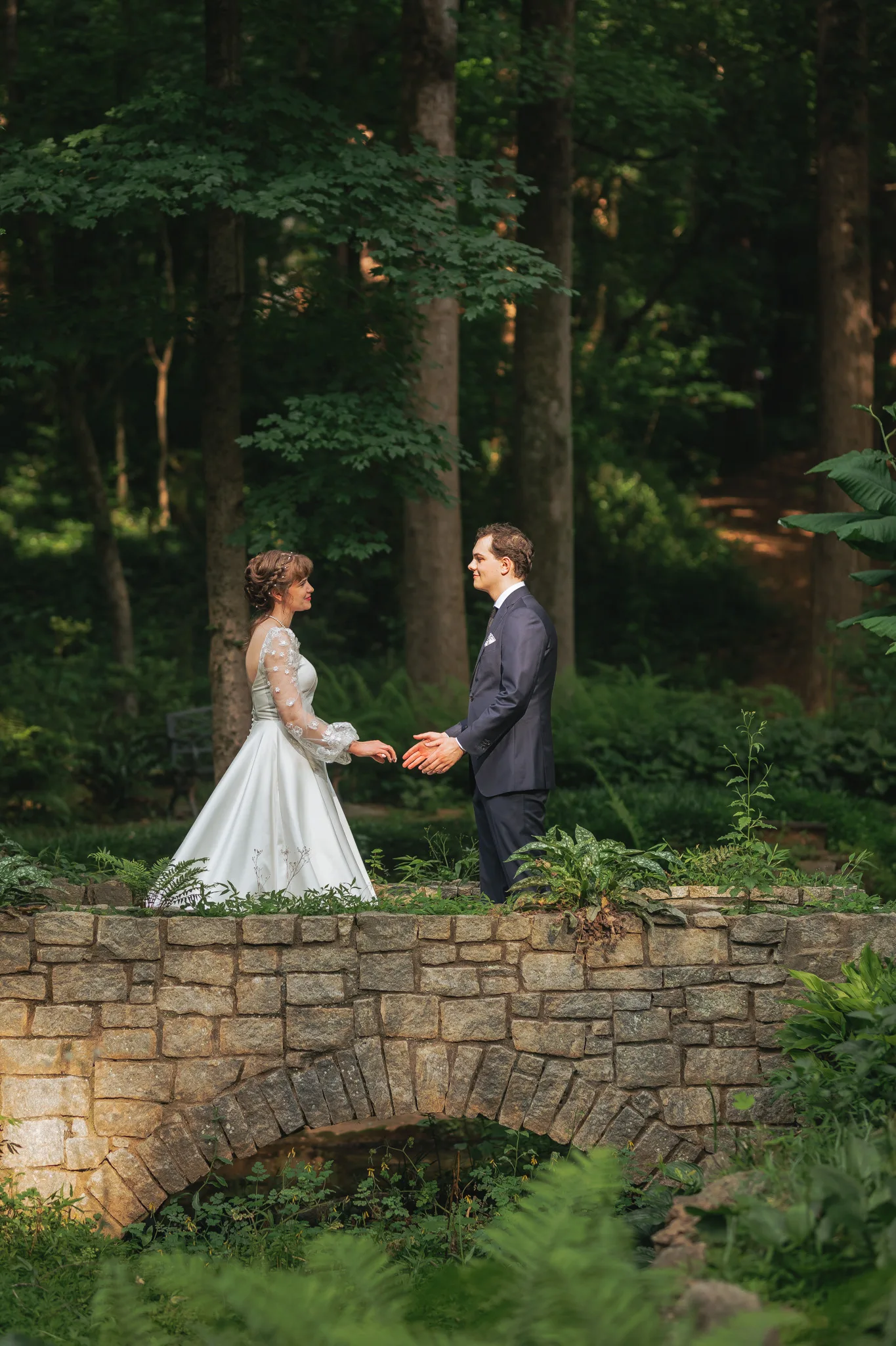 Wedding Formals: holding hands on the old stone bridge, on their wedding day at Cator Woolford Gardens in Atlanta, GA