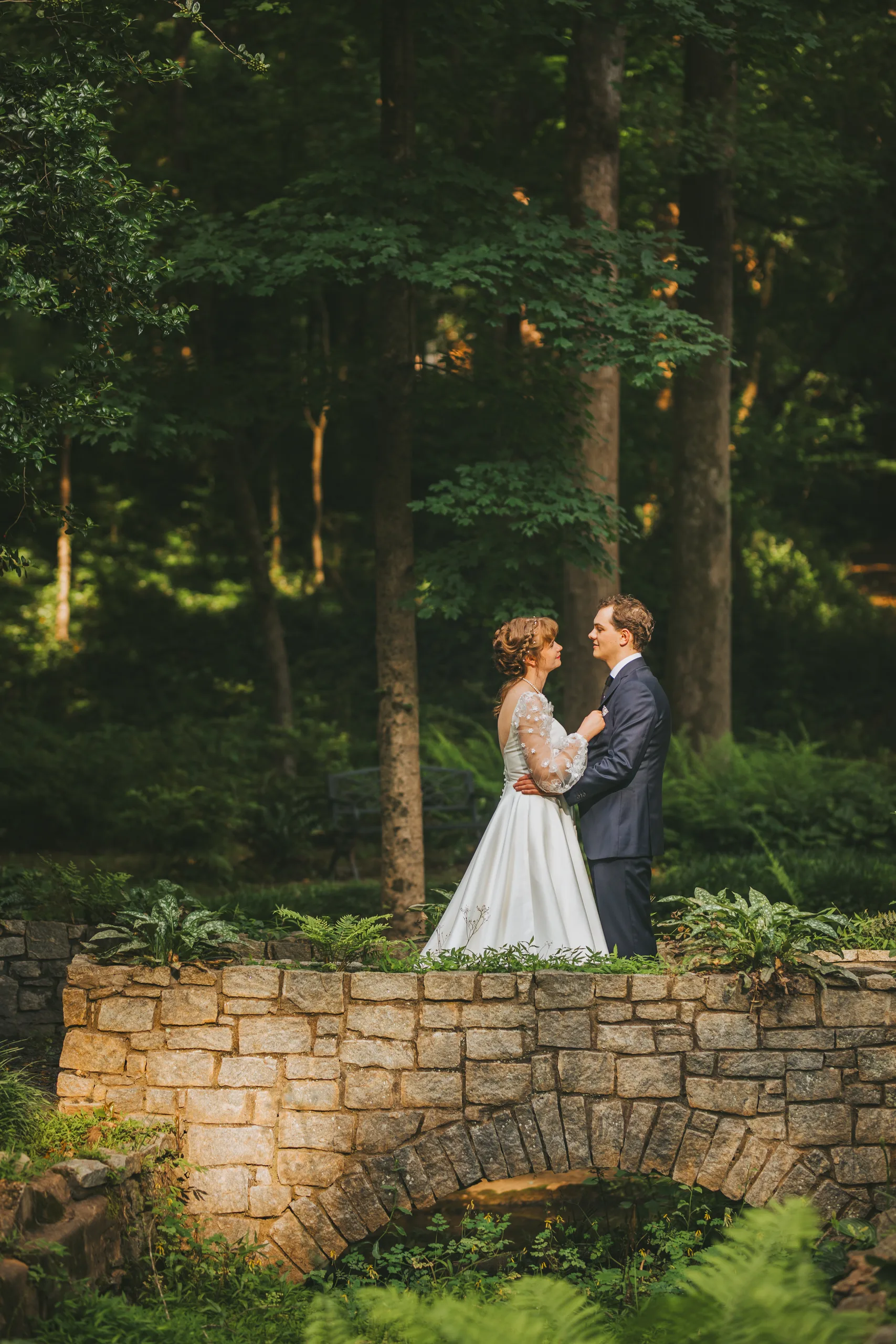 Wedding Formals: an embrace on the stone bridge in the woods, on their wedding day at Cator Woolford Gardens in Atlanta, GA
