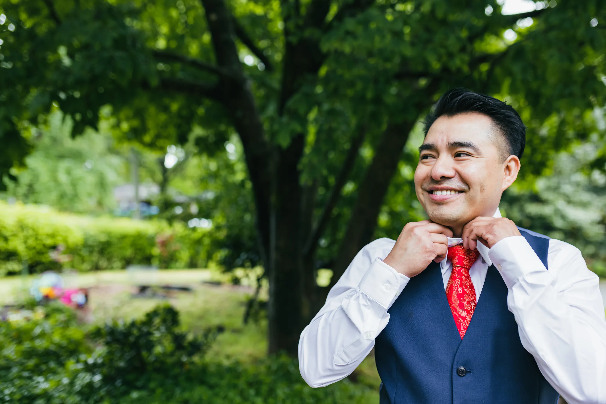 Getting Ready: the groom fixing his red tie in the garden before their wedding at the Payne-Corley House in Duluth, GA