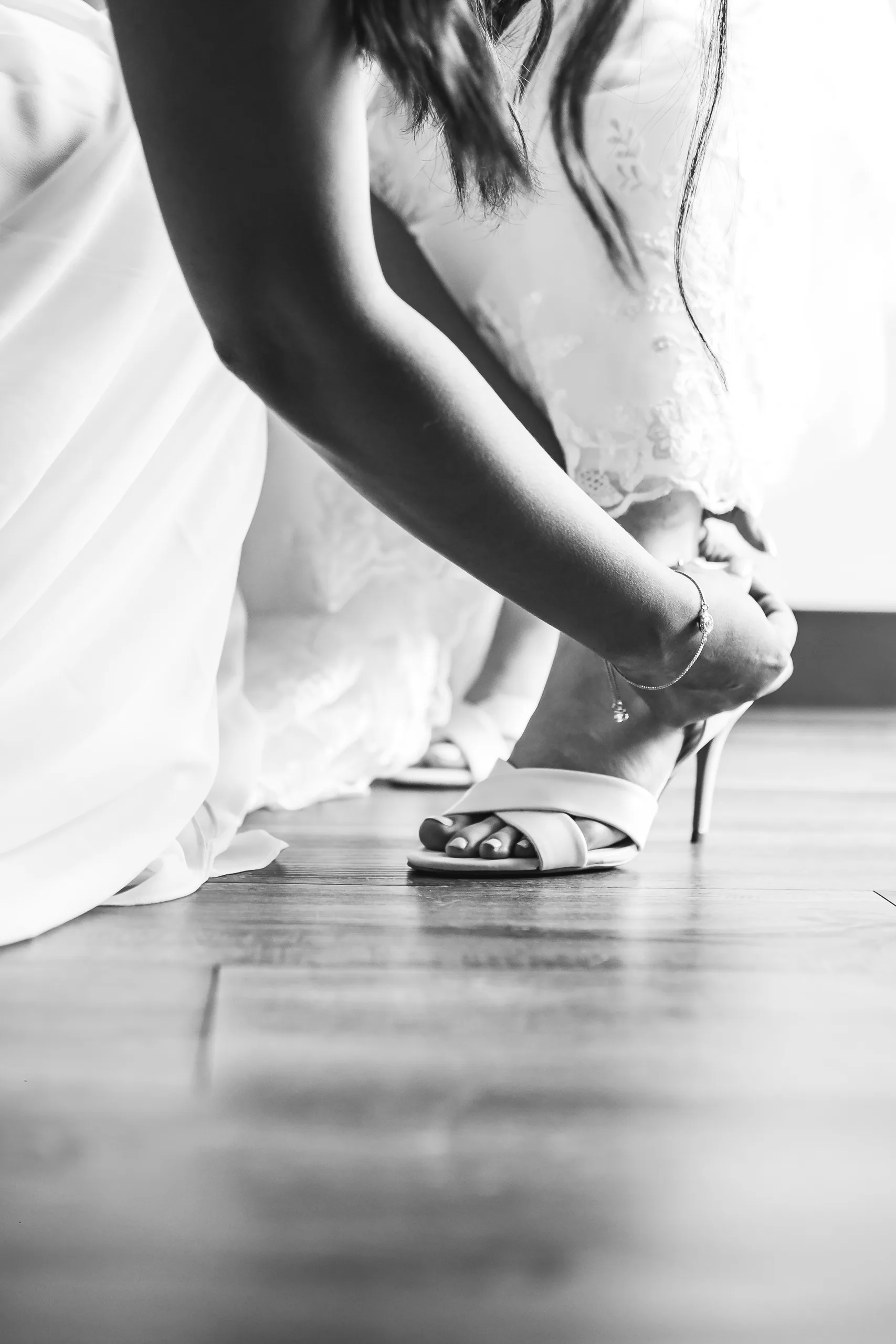 Getting Ready: the bride buckling her heels, in black and white before their wedding at Holy Cross Catholic Church in Atlanta, GA