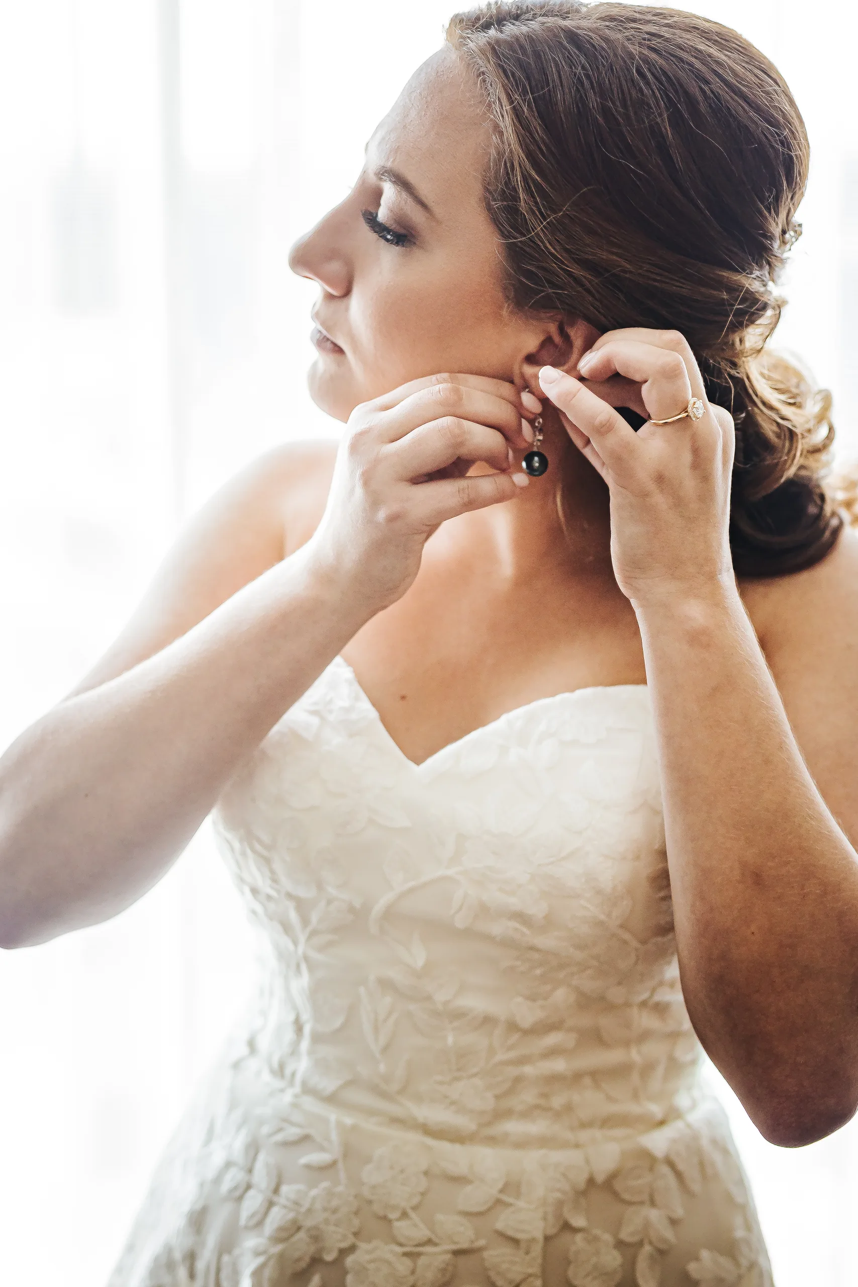 Getting Ready: the bride putting in her earring before their wedding at the Omni Hotel at The Battery in Atlanta, GA