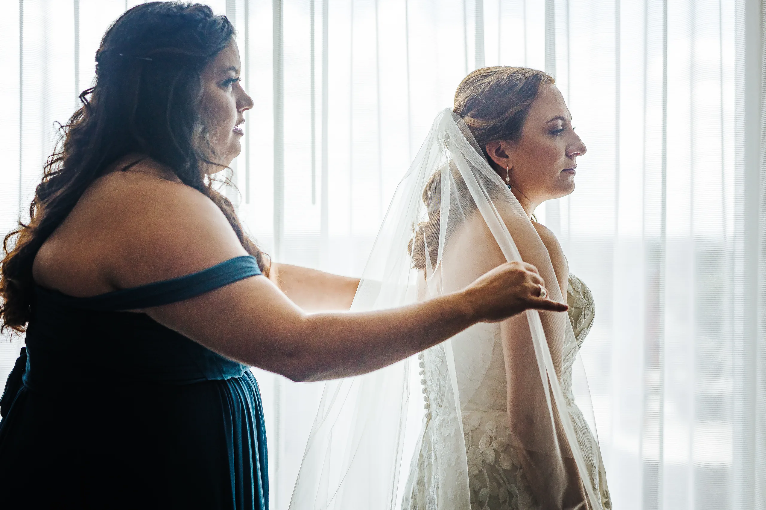 Getting Ready: a bridesmaid in teal placing her veil before their wedding at the Omni Hotel at The Battery in Atlanta, GA