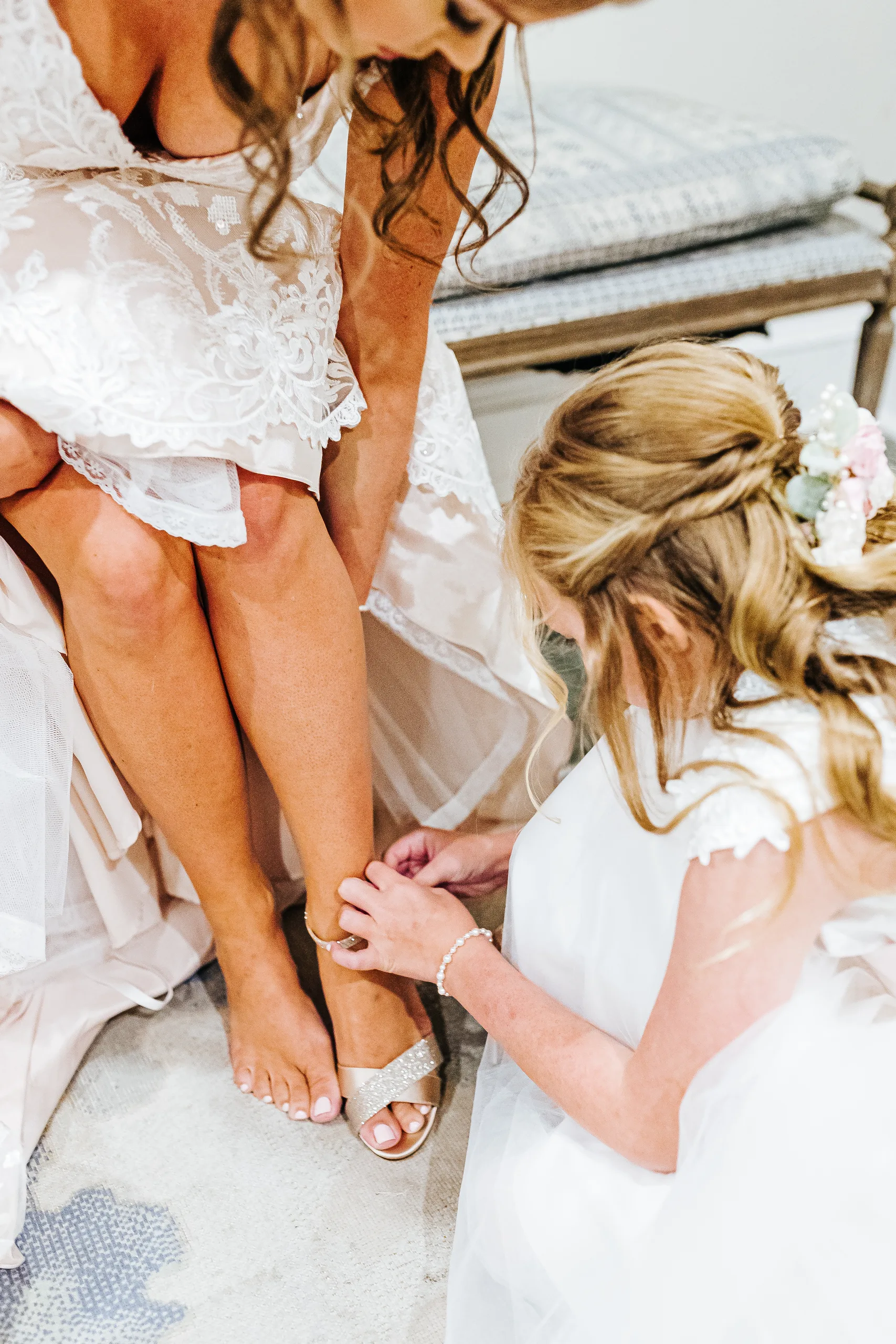 Getting Ready: a flower girl buckling the bride's sandal, before their wedding at The Piedmont Room in Atlanta, GA