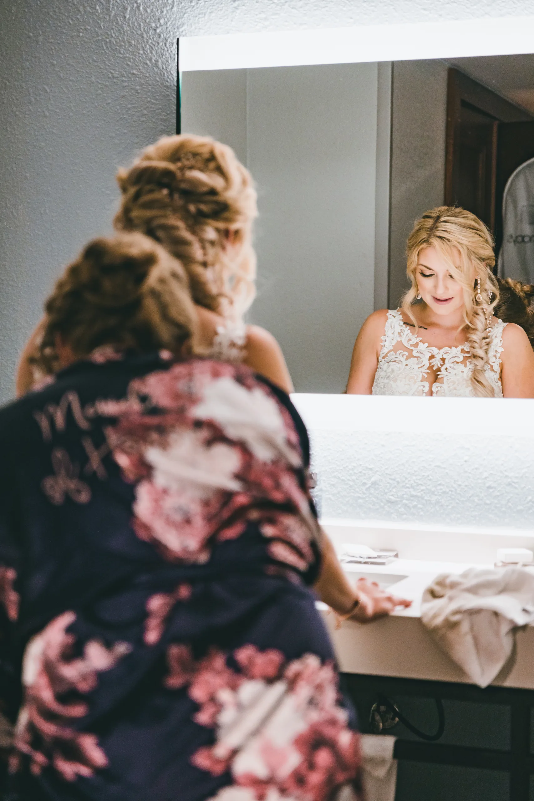 Getting Ready: the bride in the mirror as a bridesmaid in a Mrs. robe helps her, before their wedding at Atlanta Evergreen Lakeside Resort in Stone Mountain, GA