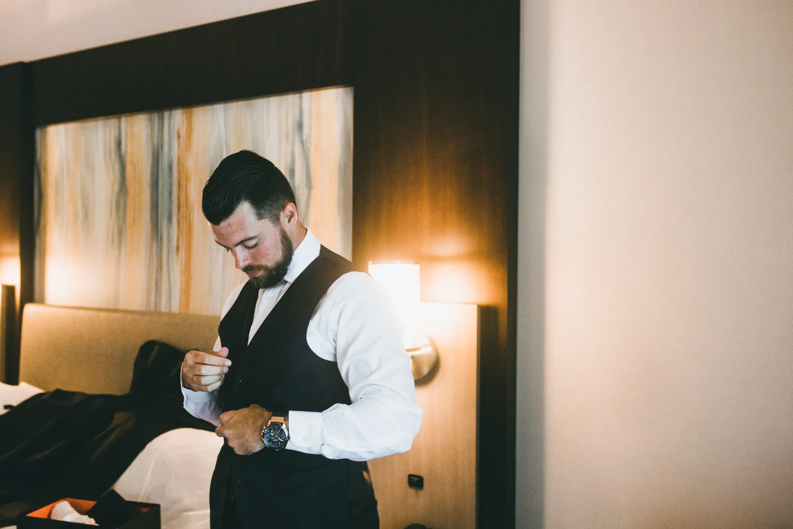 Getting Ready: the groom buttoning his navy vest, before their wedding at Atlanta Evergreen Lakeside Resort in Stone Mountain, GA