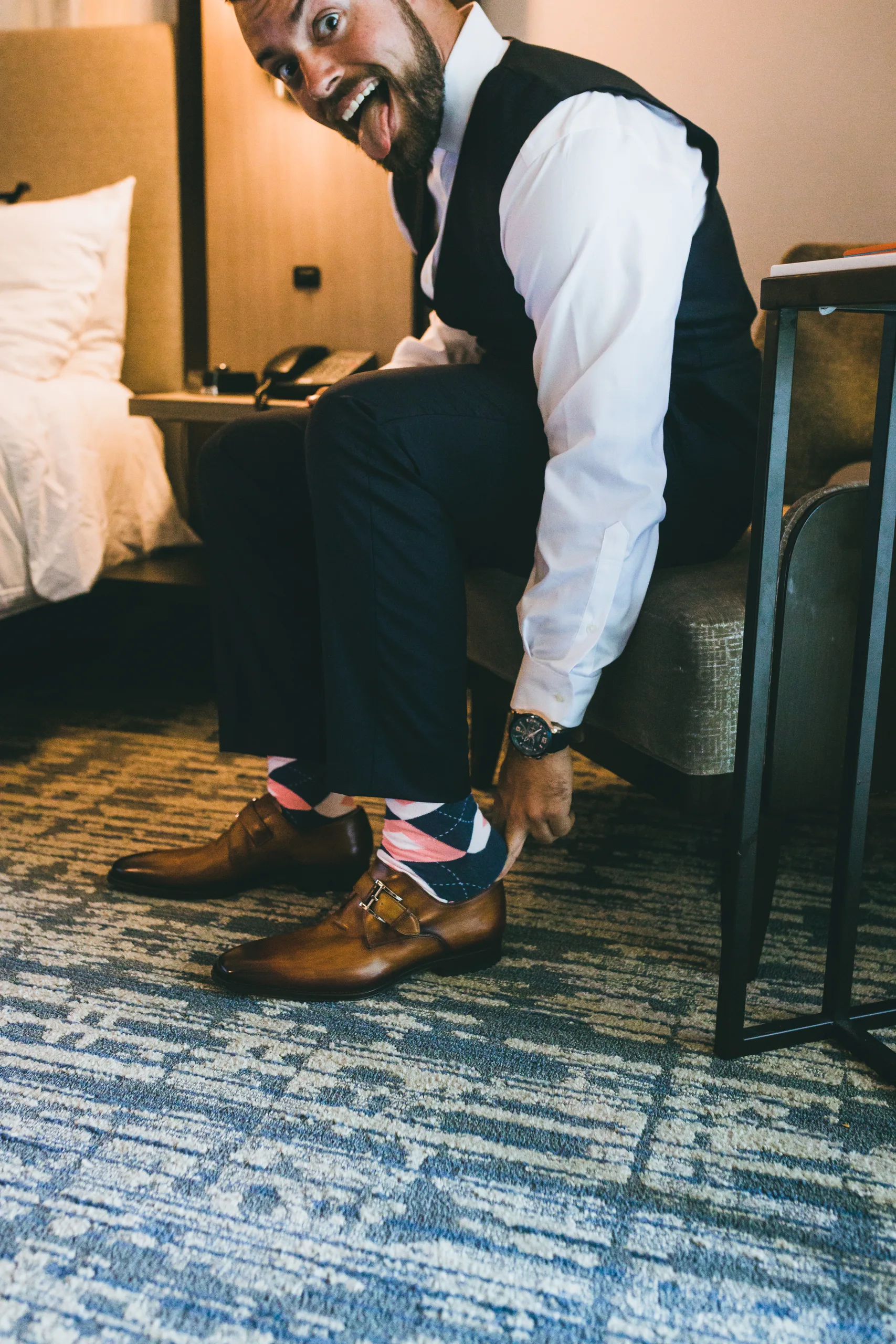 Getting Ready: the groom showing off his socks as he puts on his shoes, before their wedding at Atlanta Evergreen Lakeside Resort in Stone Mountain, GA