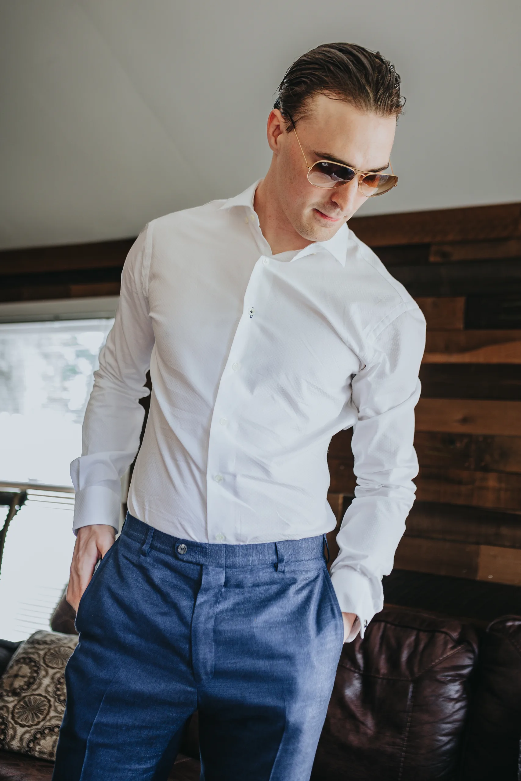 Getting Ready: the groom in sunglasses and his blue suit pants, before their wedding at The Wildflower 301 in Greensboro, GA