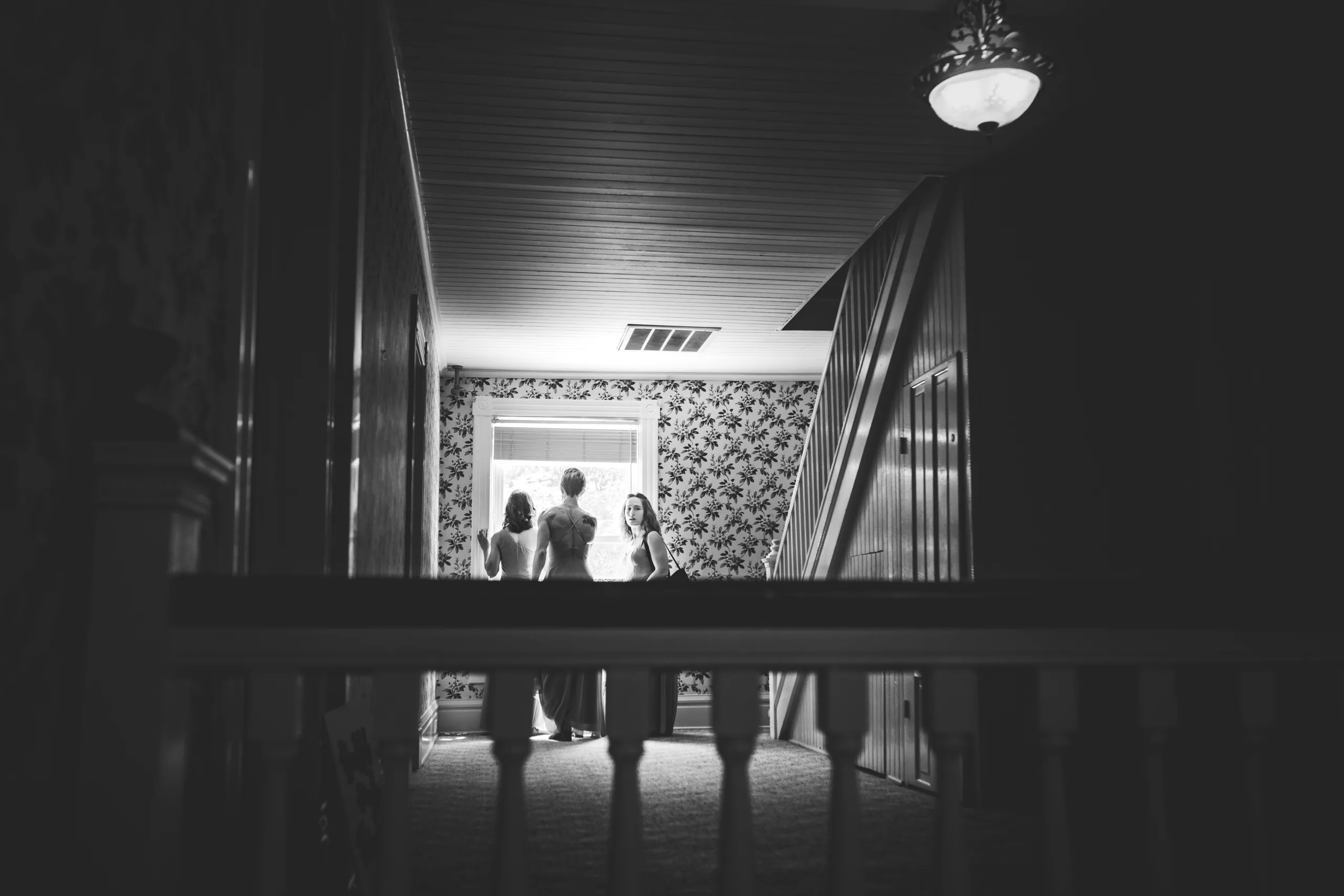 Getting Ready: the bride and her bridesmaids at the bottom of the staircase, in black and white, before their wedding at The Wildflower 301 in Greensboro, GA