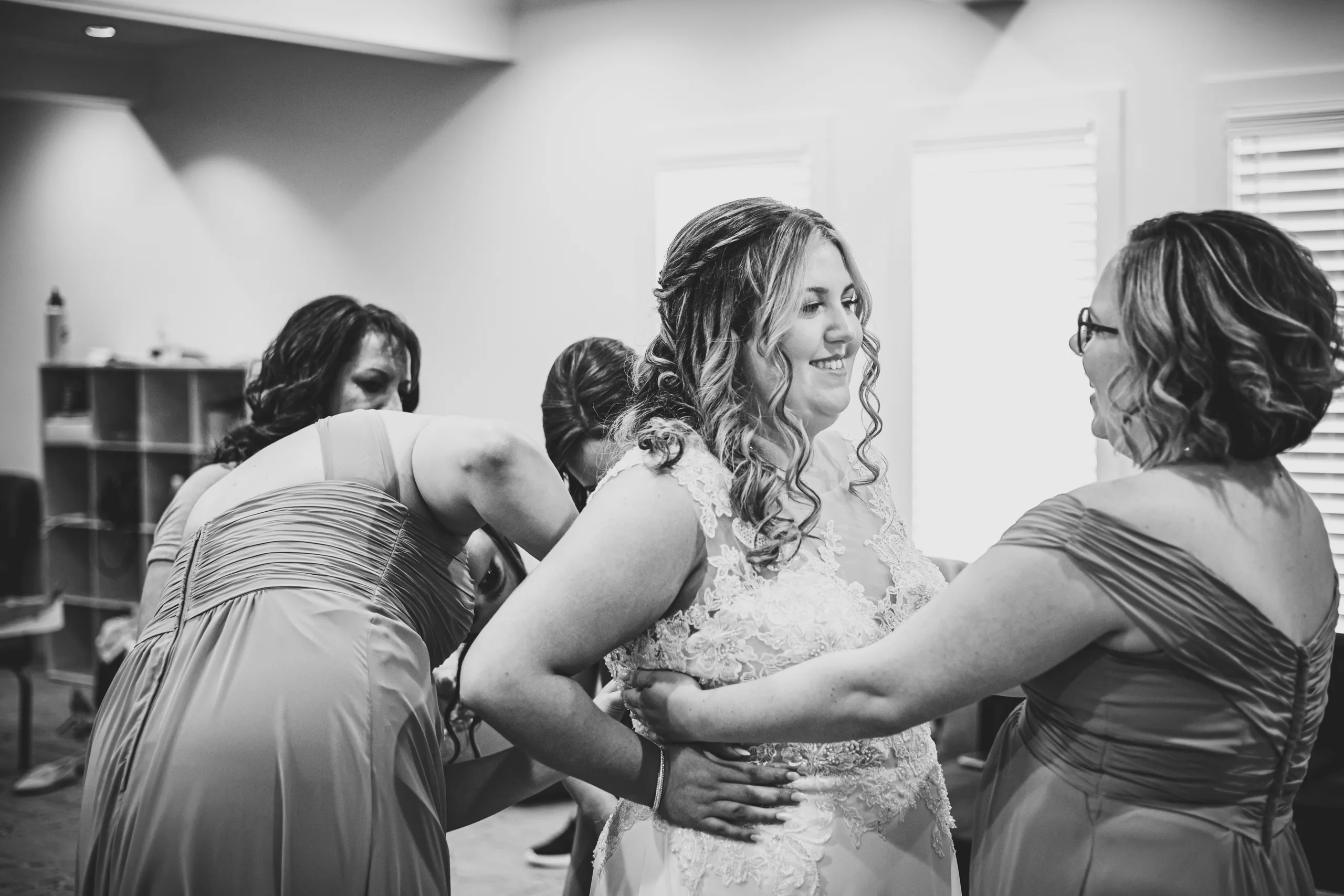 Getting Ready: her bridesmaids buttoning her gown, in black and white before their wedding at the Country Club of Roswell in Roswell, GA
