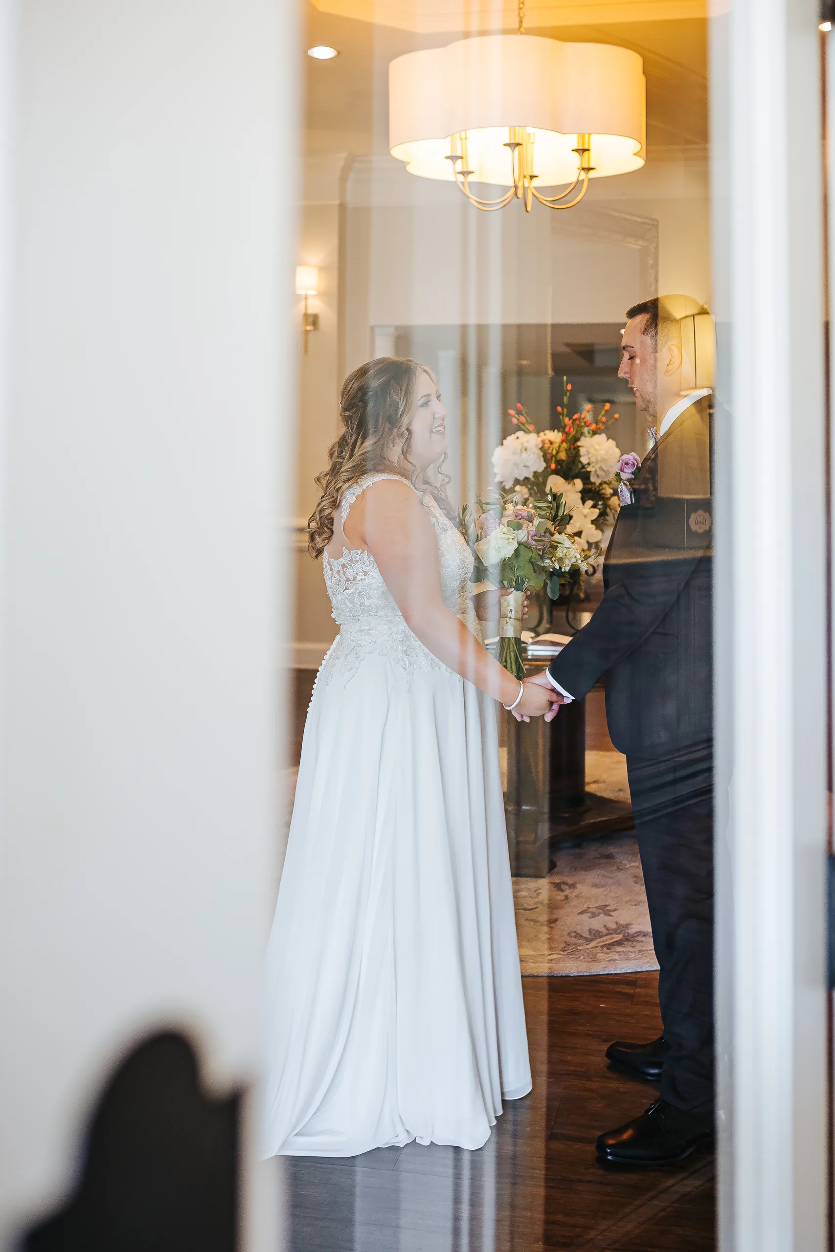First Look: holding hands seen through the glass door before their wedding at the Country Club of Roswell in Roswell, GA