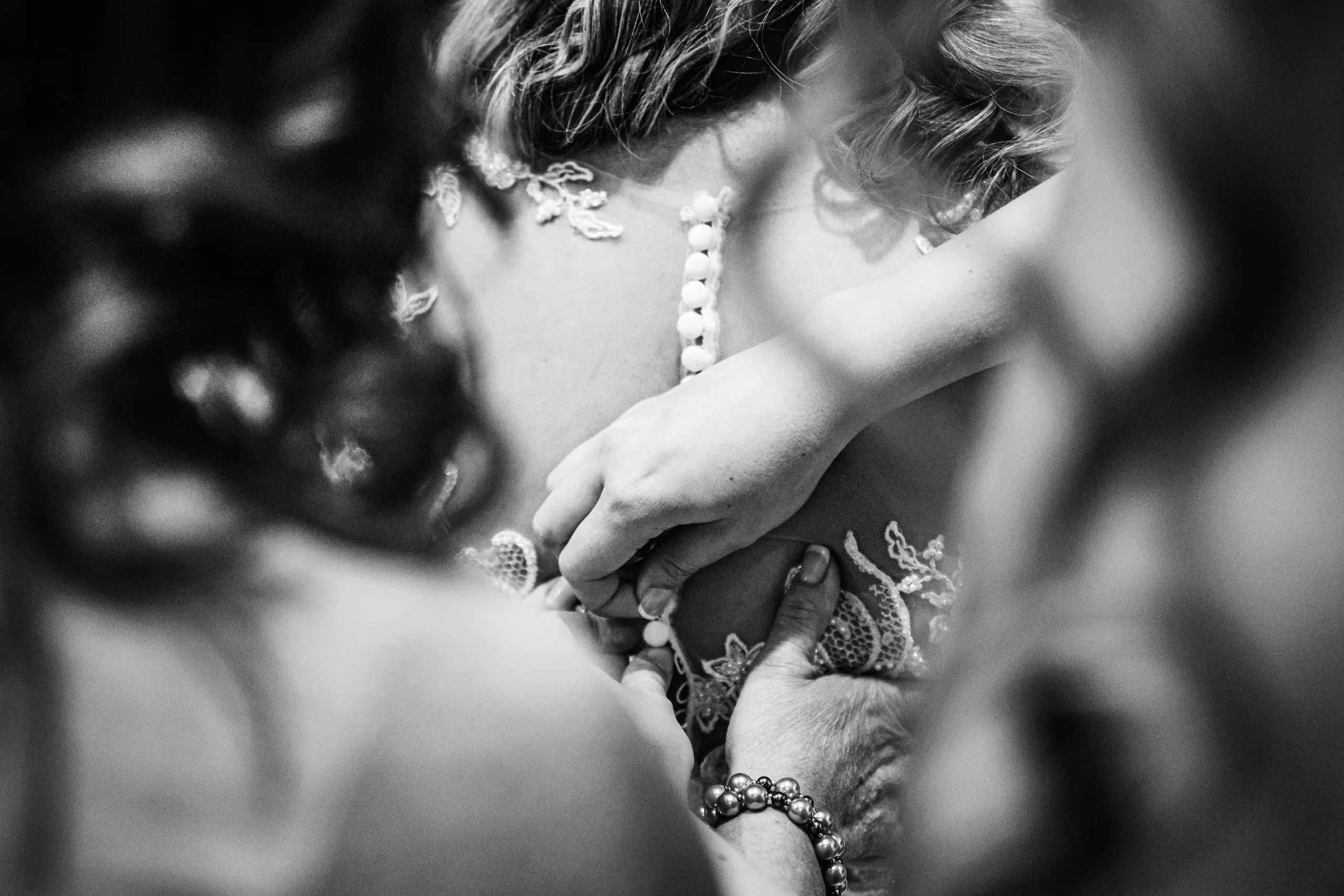 Getting Ready: hands buttoning the back of her gown, in black and white before their wedding at the Country Club of Roswell in Roswell, GA