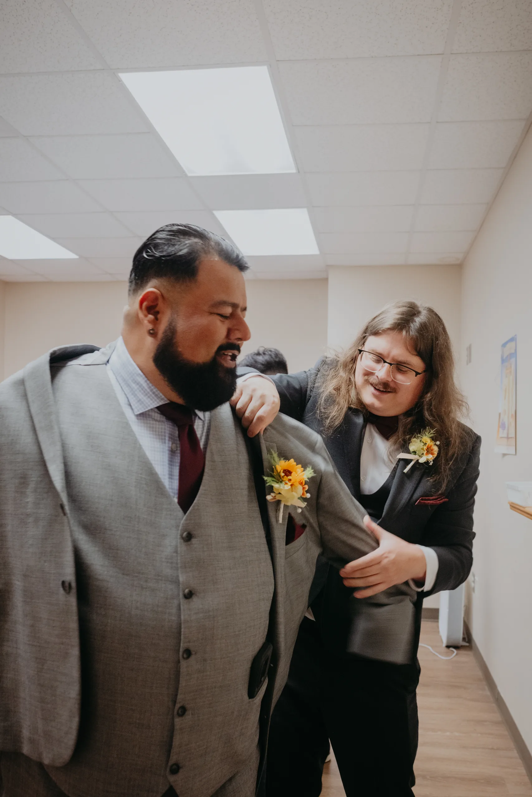 Getting Ready: a groomsman helping the groom into his jacket, before their wedding at St. Lawrence Catholic Church in Lawrenceville, GA