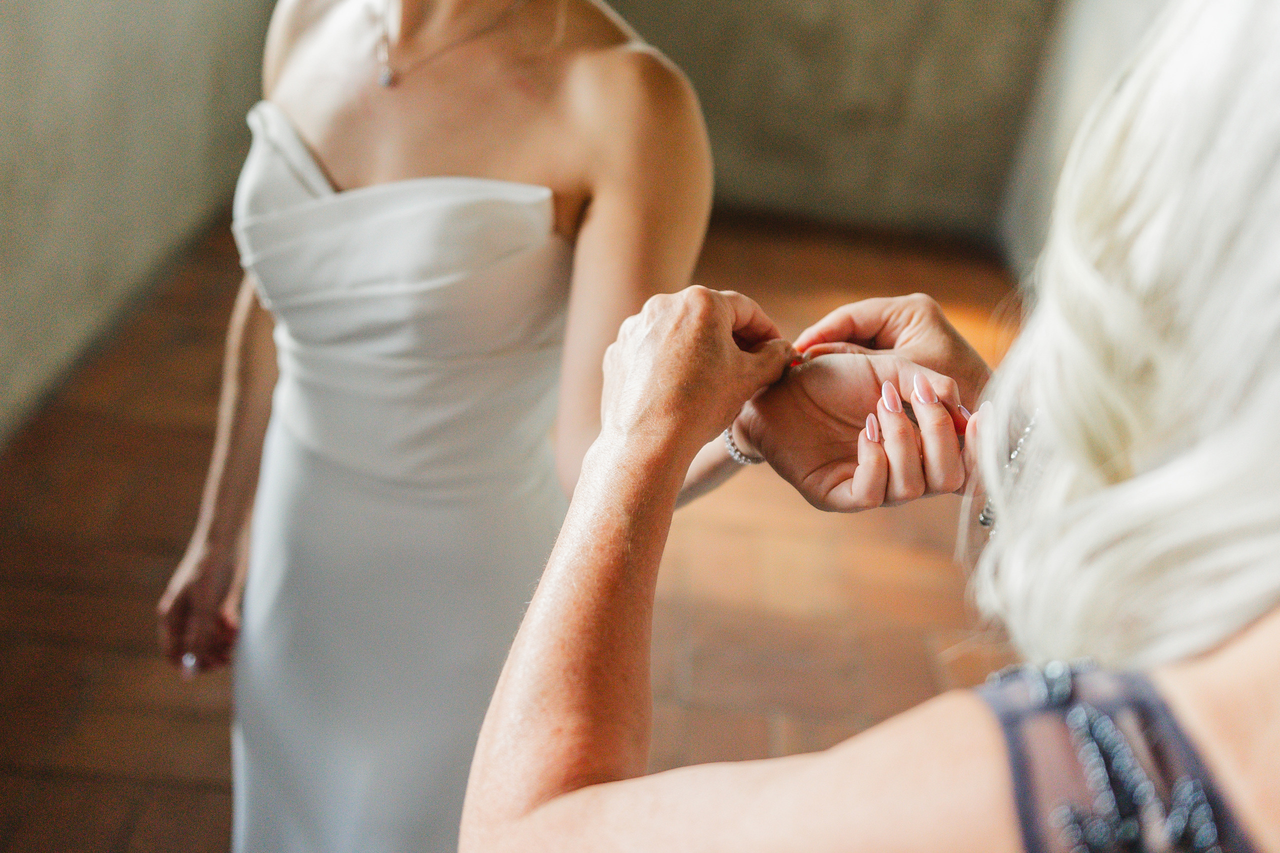 Getting Ready: her bracelet being fastened, the gown just on, before their wedding at Summerour Studio in Atlanta, GA