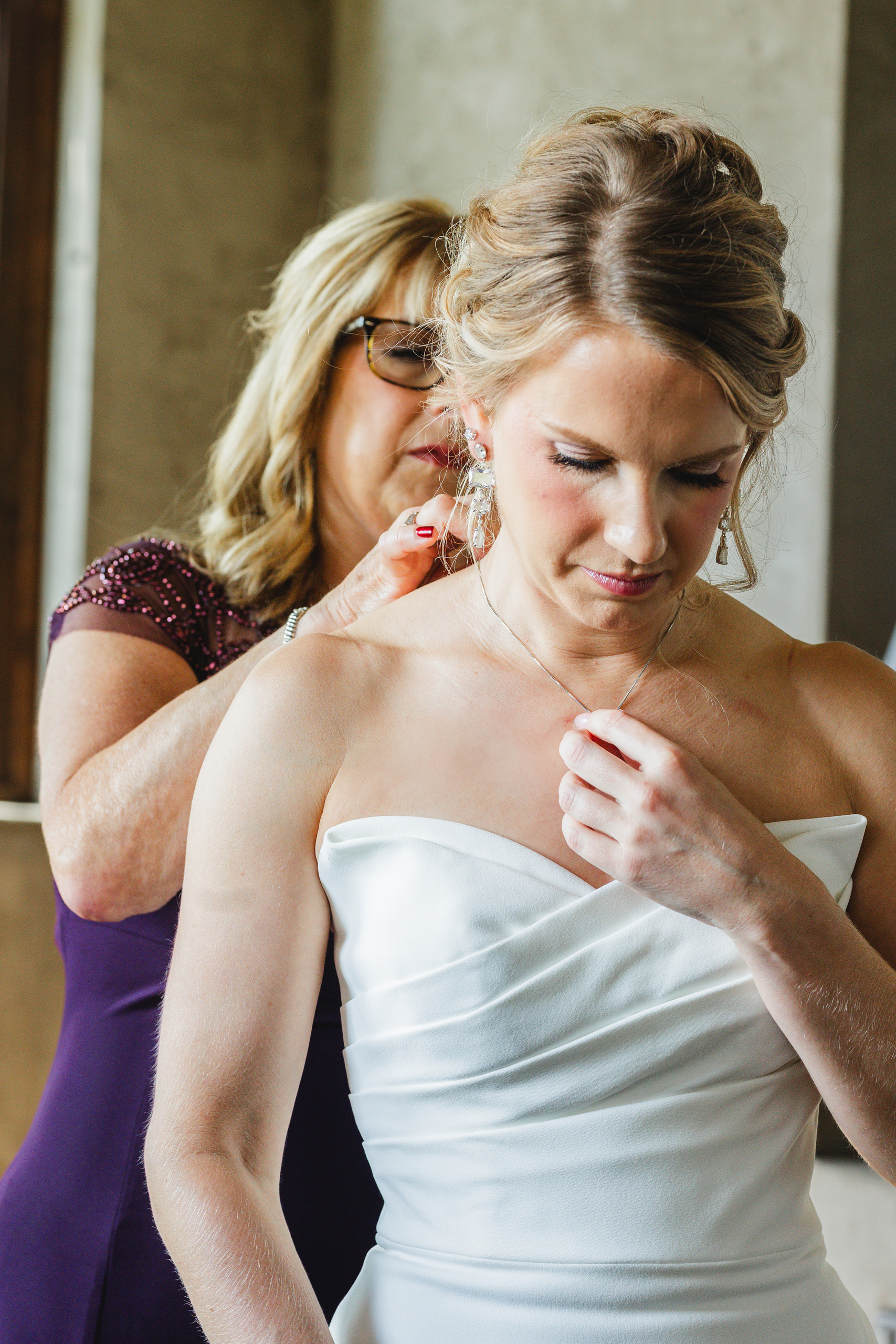 Getting Ready: her mother fastening her necklace, before their wedding at Summerour Studio in Atlanta, GA