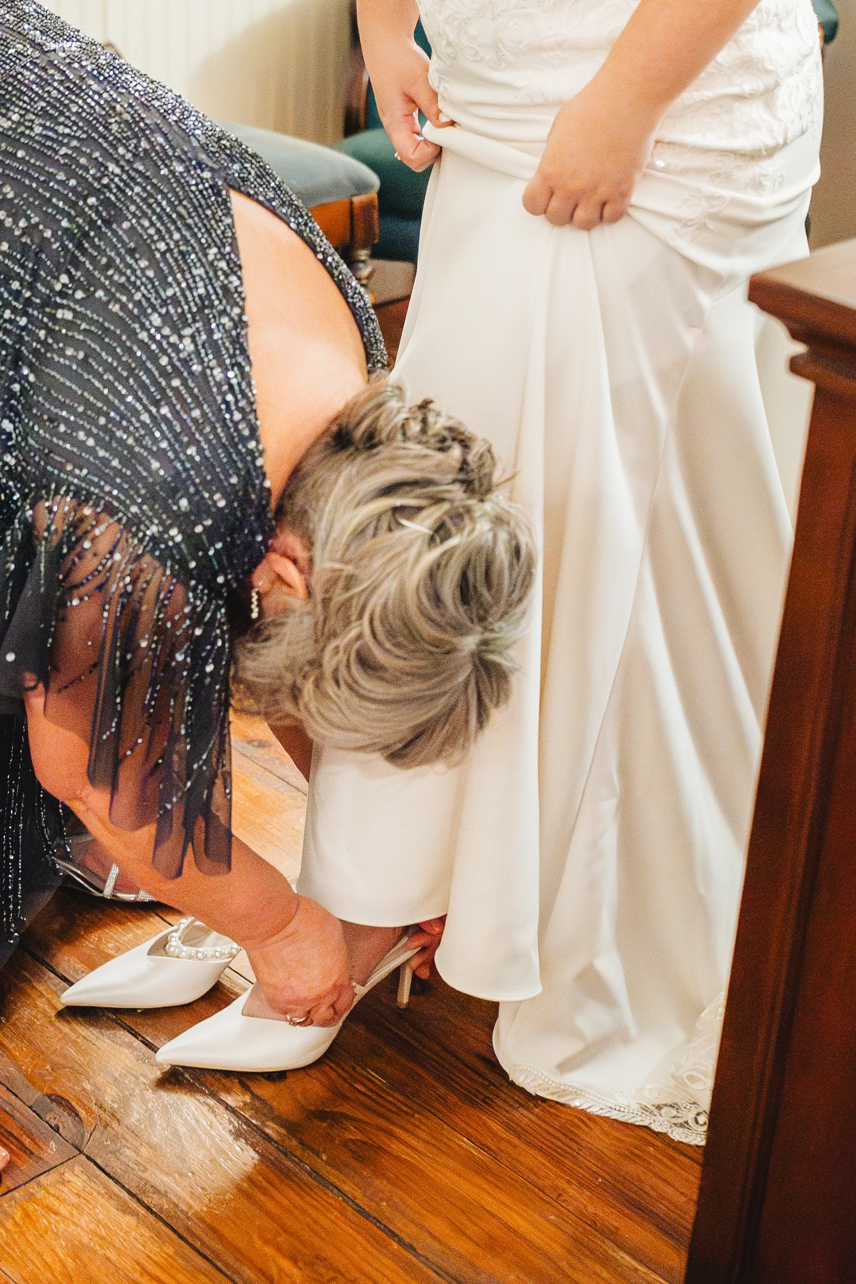 Getting Ready: her mom helping with her shoes before their wedding at Ivy Hall at Roswell Mill in Roswell, GA