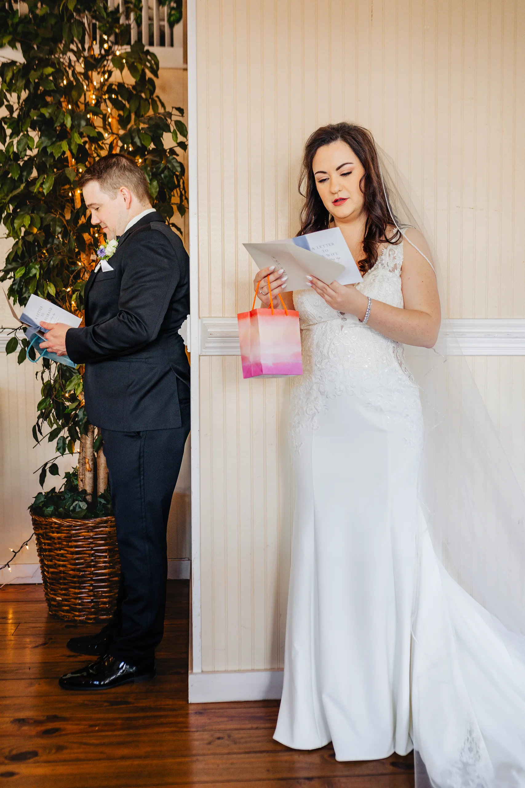 Wedding Details: the bride and groom reading letters on either side of a wall at their wedding at Ivy Hall at Roswell Mill in Roswell, GA