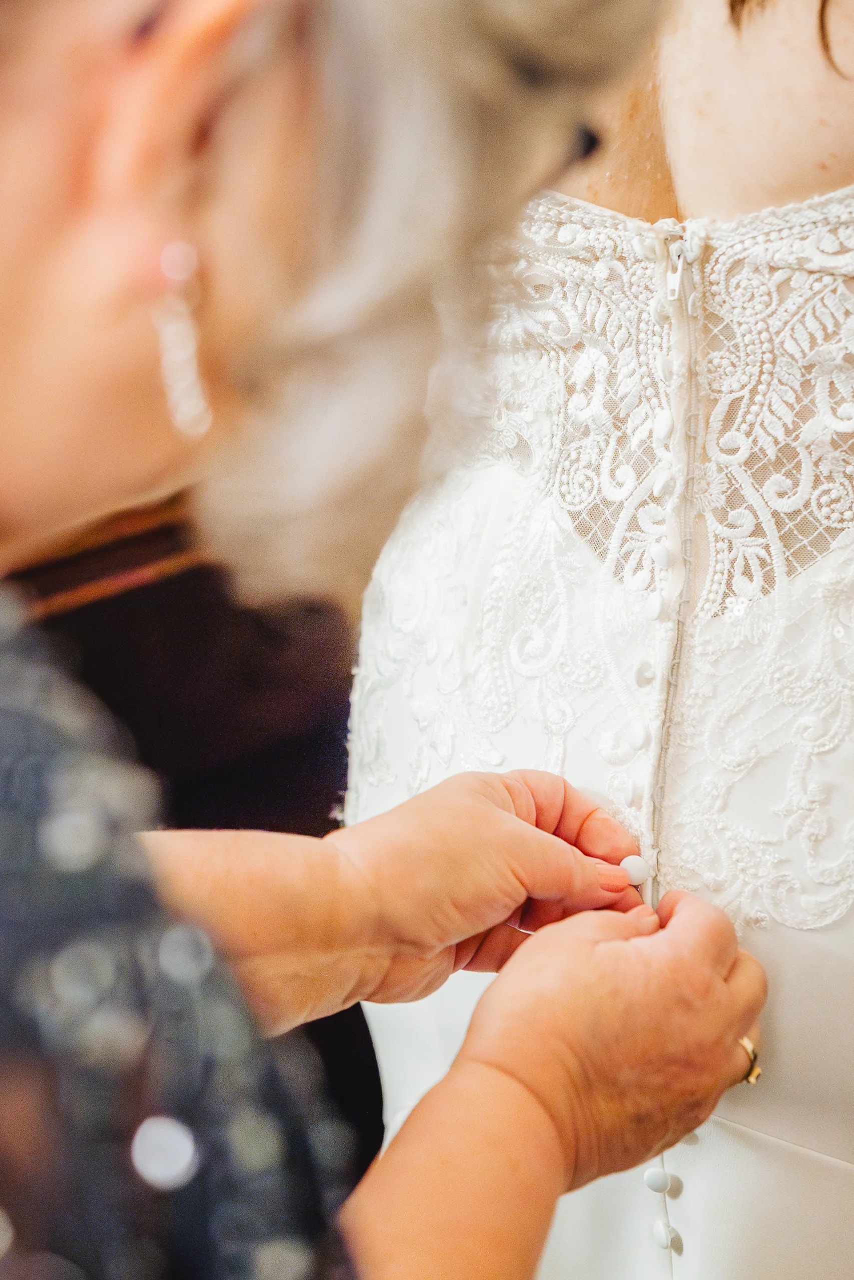 Getting Ready: her mom buttoning the back of her gown before their wedding at Ivy Hall at Roswell Mill in Roswell, GA