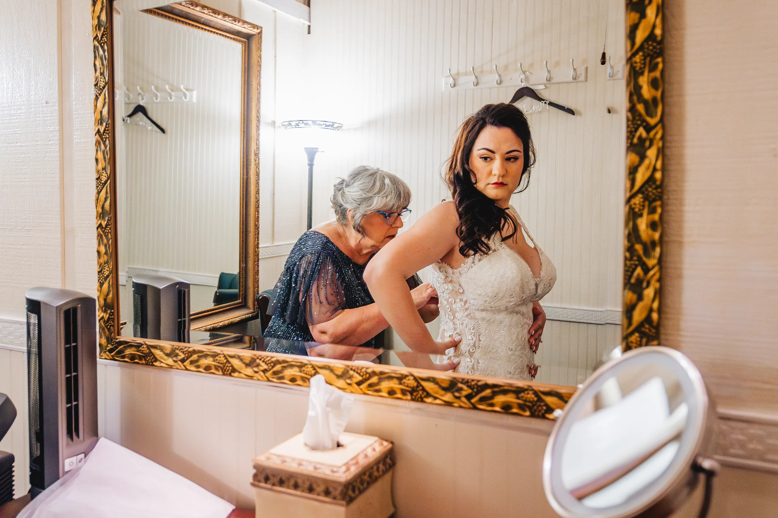 Getting Ready: her mom lacing up her gown in the mirror before their wedding at Ivy Hall at Roswell Mill in Roswell, GA
