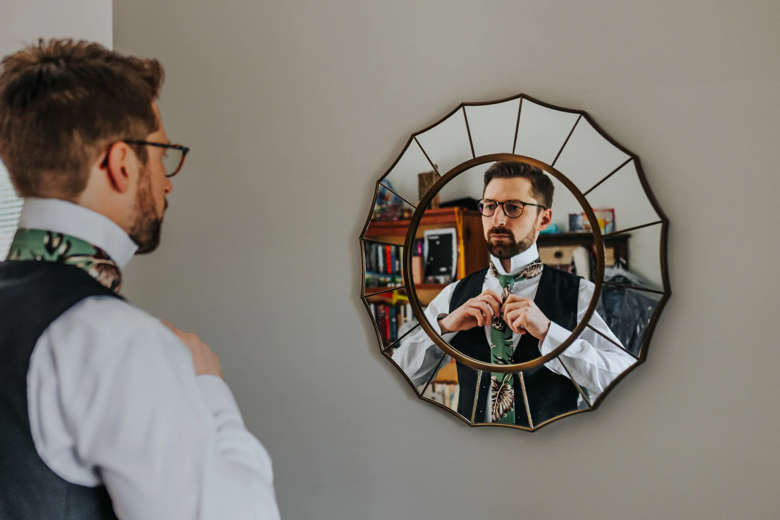 Getting Ready: the groom tying his tie in a round mirror, before their wedding at Terminus 330 in Atlanta, GA
