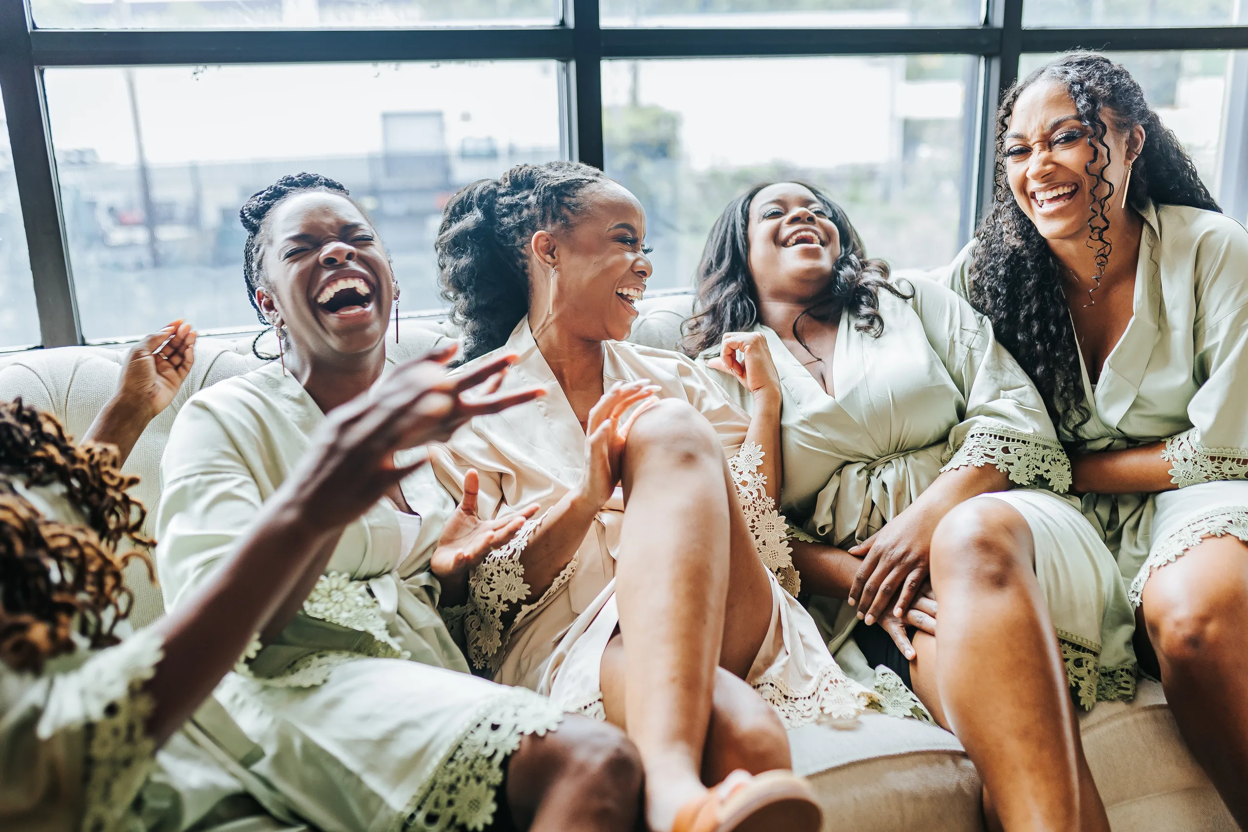 Getting Ready: the bride and her bridesmaids laughing on the sofa in their robes, before their wedding at Terminus 330 in Atlanta, GA