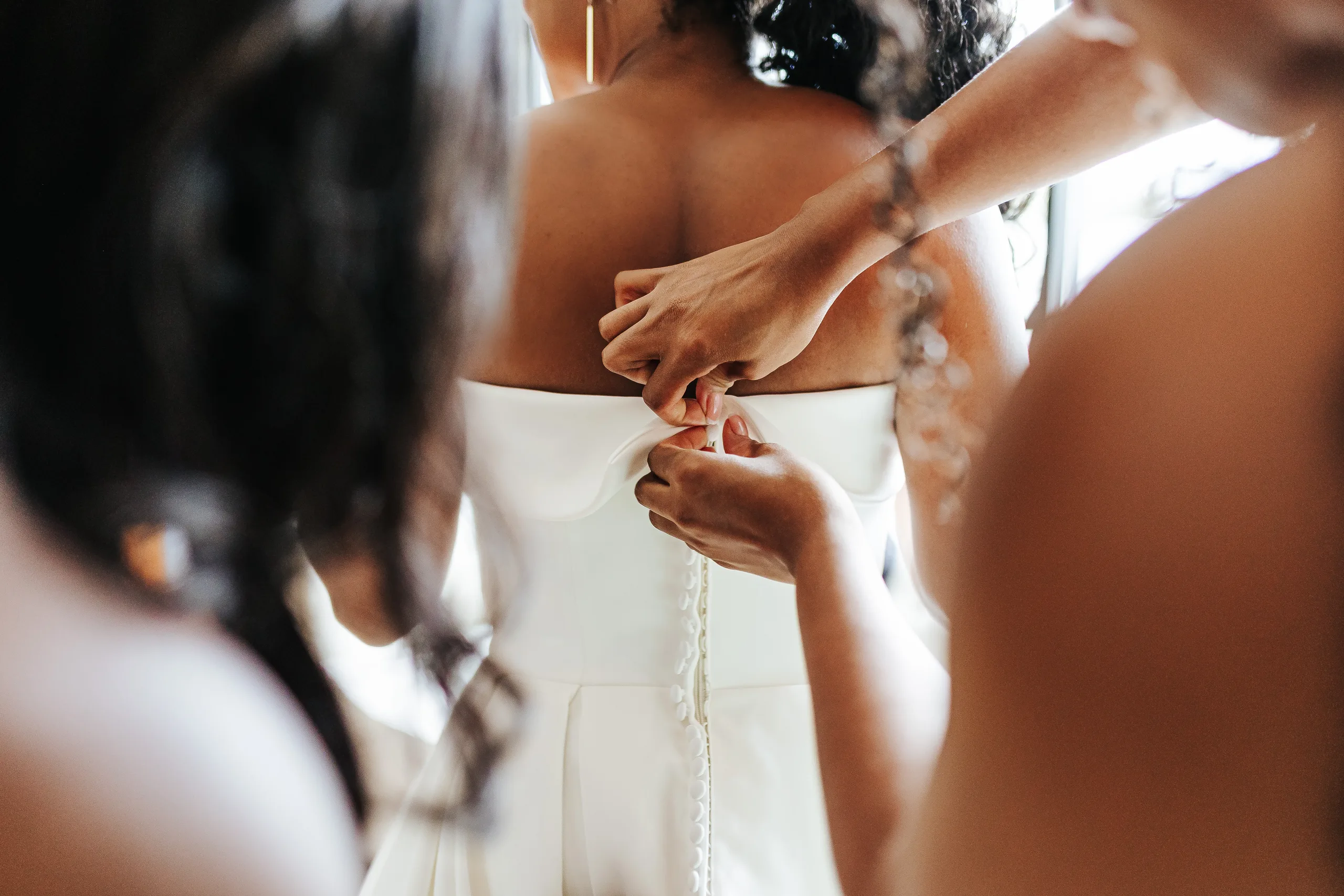 Getting Ready: buttoning up the back of her gown, before their wedding at Terminus 330 in Atlanta, GA