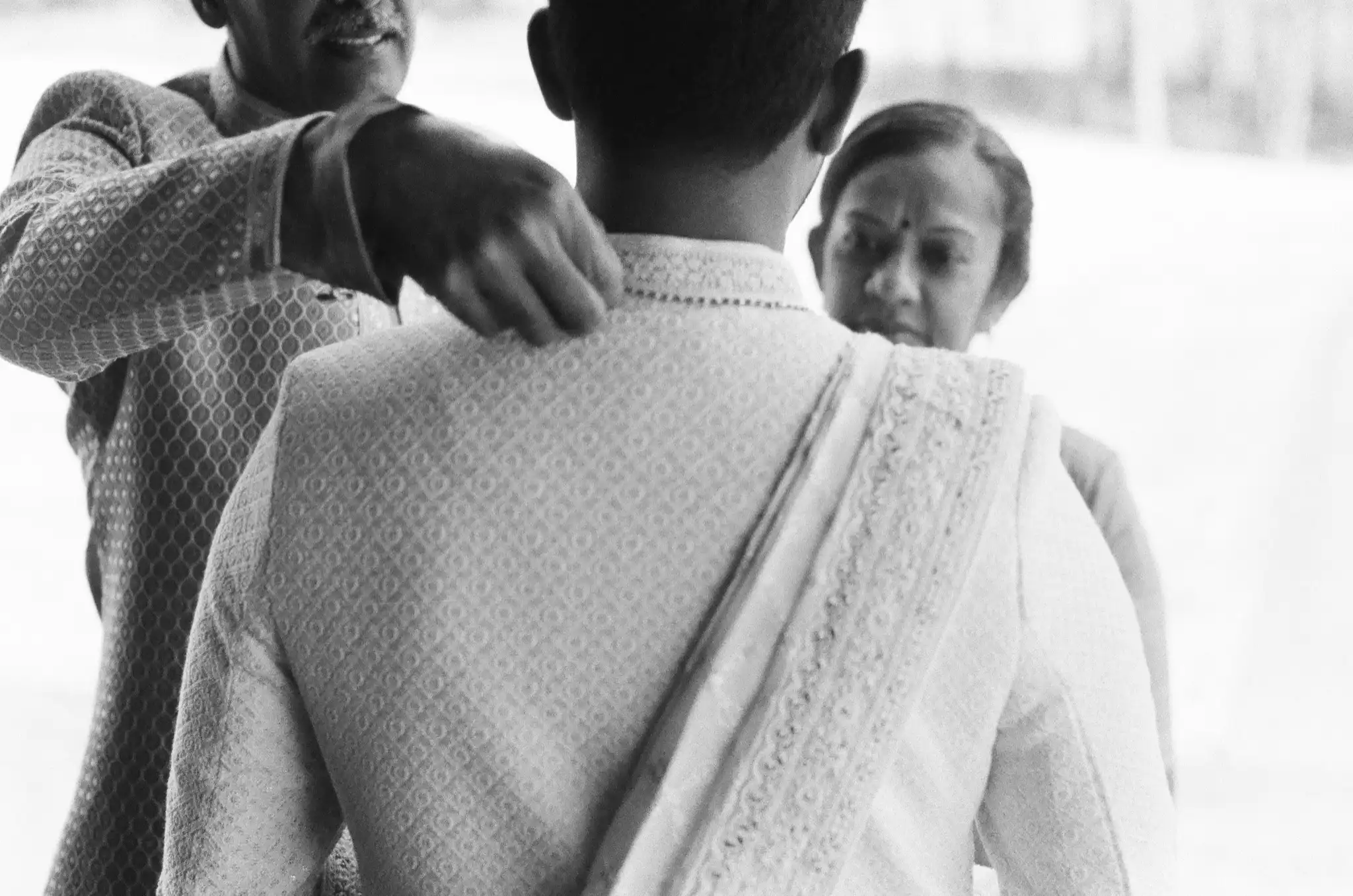 Groom's family helping him into his sherwani before the wedding, in black and white on 35mm film at The Venue at Sharp Mountain in Jasper, Georgia