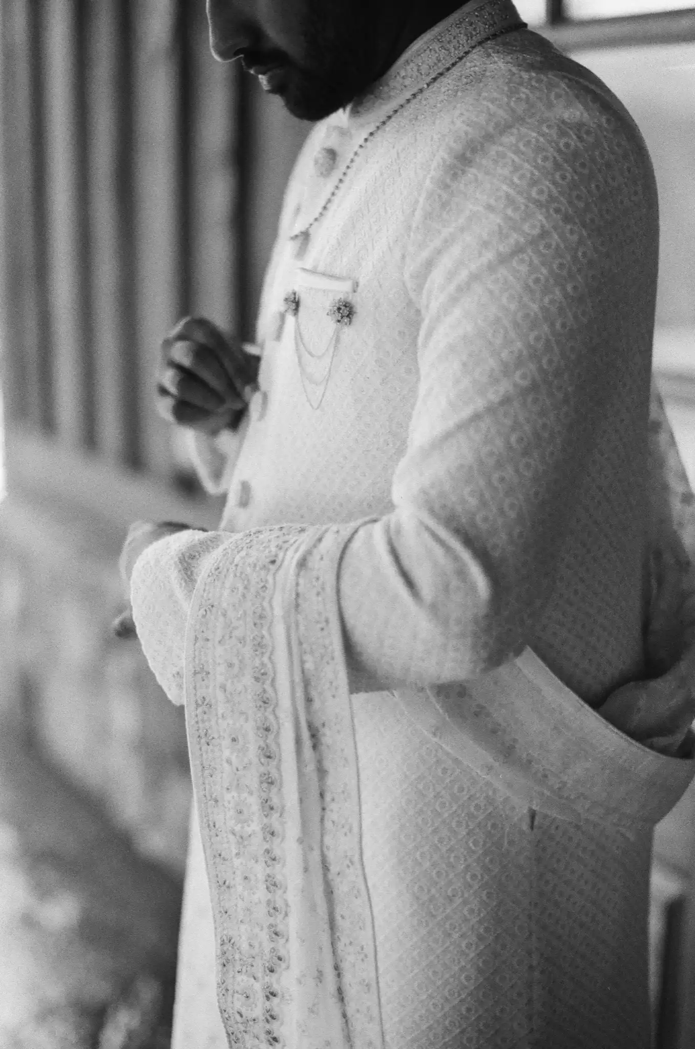 Groom adjusting his embroidered sherwani and dupatta before the ceremony, in black and white on 35mm film at The Venue at Sharp Mountain in Jasper, Georgia