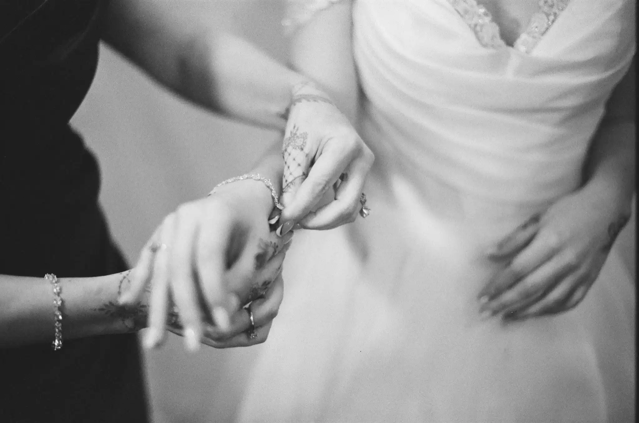 Henna-covered hands fastening the bride's bracelet before the ceremony, in black and white on 35mm film at The Venue at Sharp Mountain in Jasper, Georgia