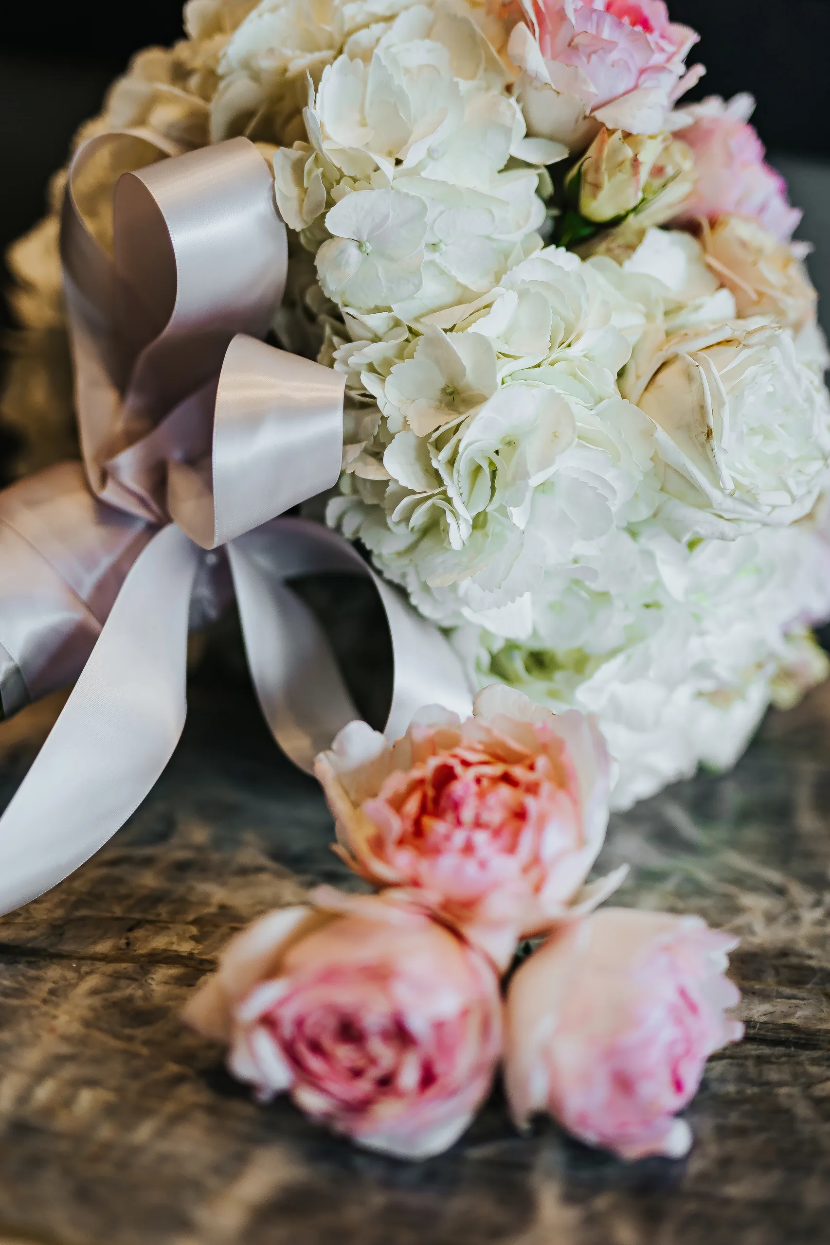 Wedding Florals: her bouquet of pink and white roses wrapped in ribbon at a wedding at the Omni Hotel at The Battery in Atlanta, GA