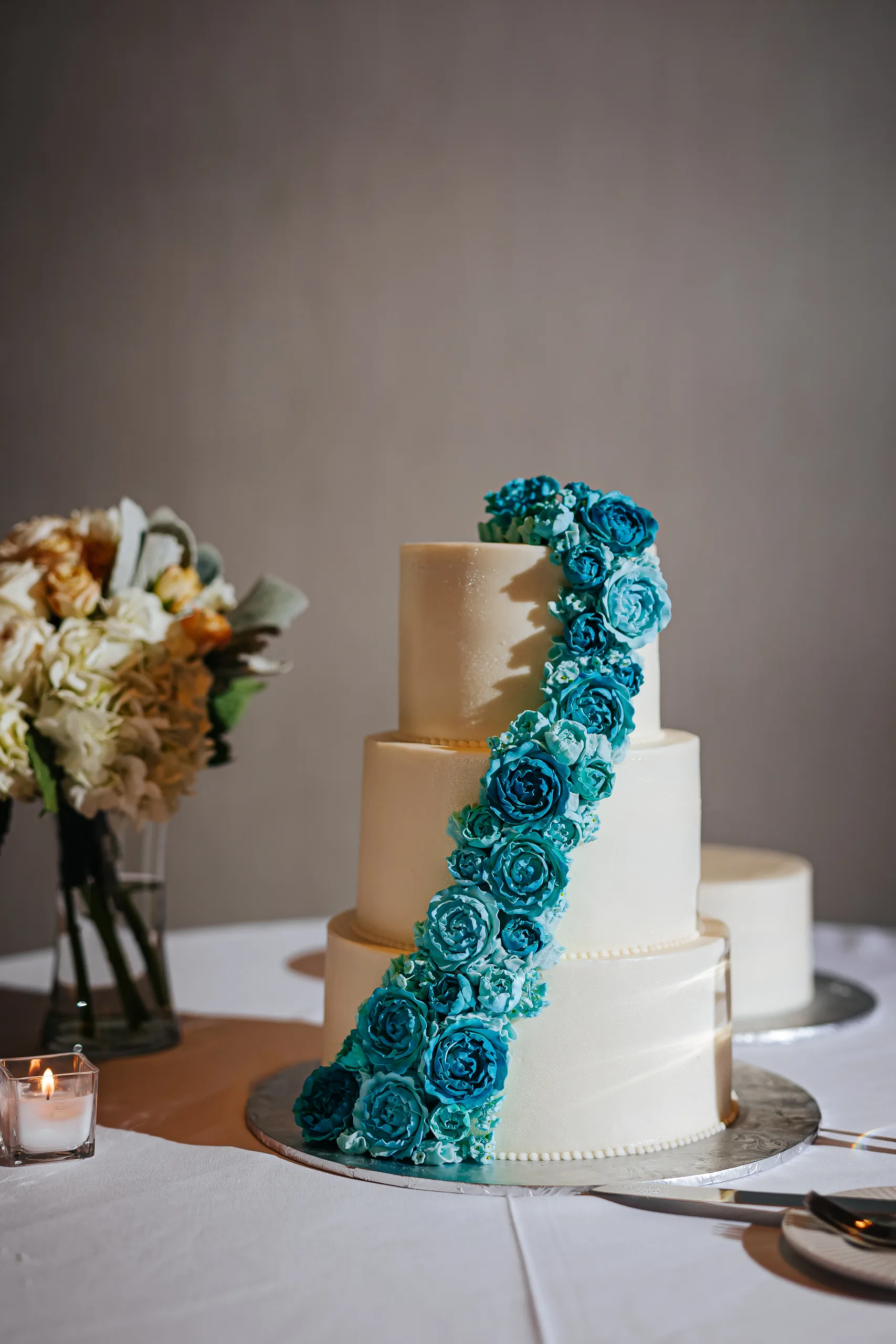 Wedding Cake Details: the white cake with a cascade of teal roses at a wedding at the Omni Hotel at The Battery in Atlanta, GA