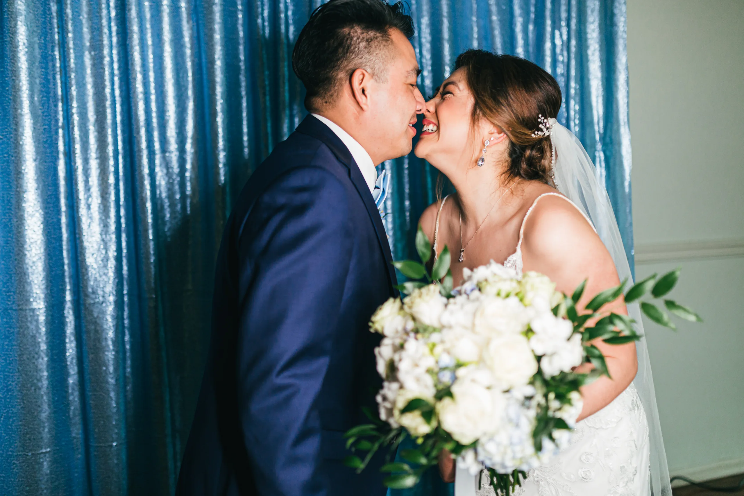Reception: a kiss in front of the blue curtain at their wedding at the Payne-Corley House in Duluth, GA