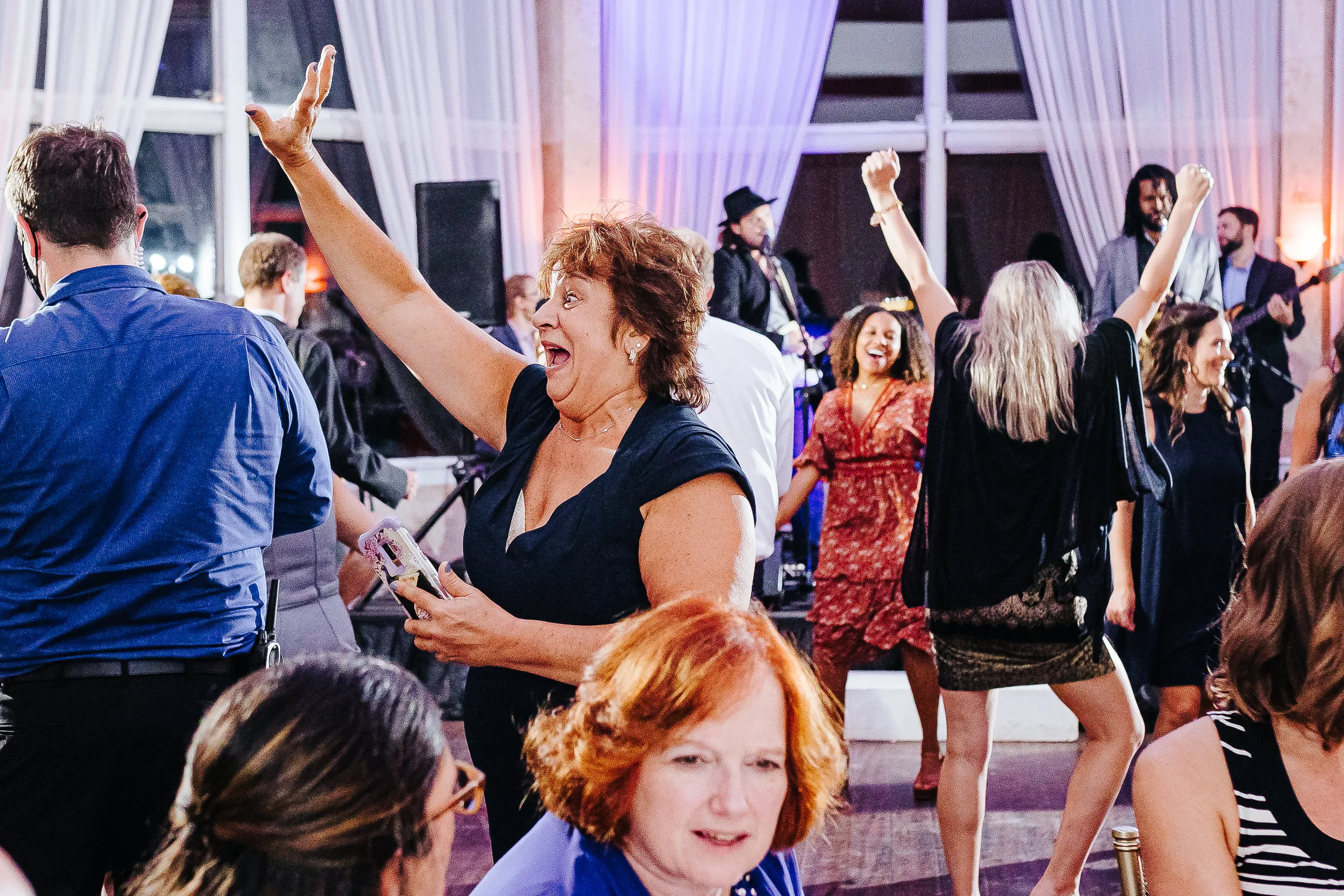 Reception: a guest with her arms up on the dance floor, at their wedding at The Piedmont Room in Atlanta, GA