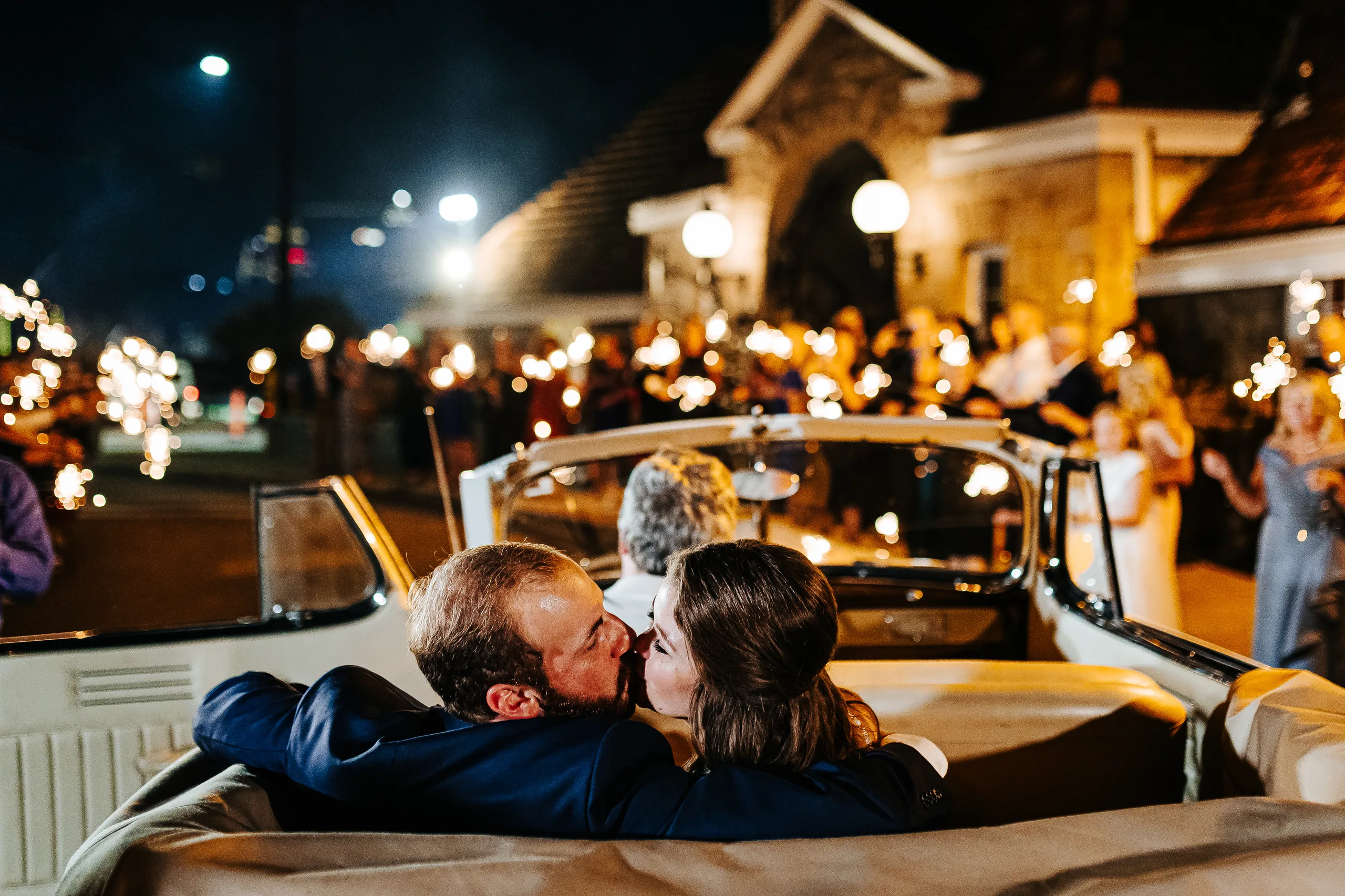Send-Off: a kiss in the back of the convertible as guests wave sparklers, at their wedding at The Piedmont Room in Atlanta, GA