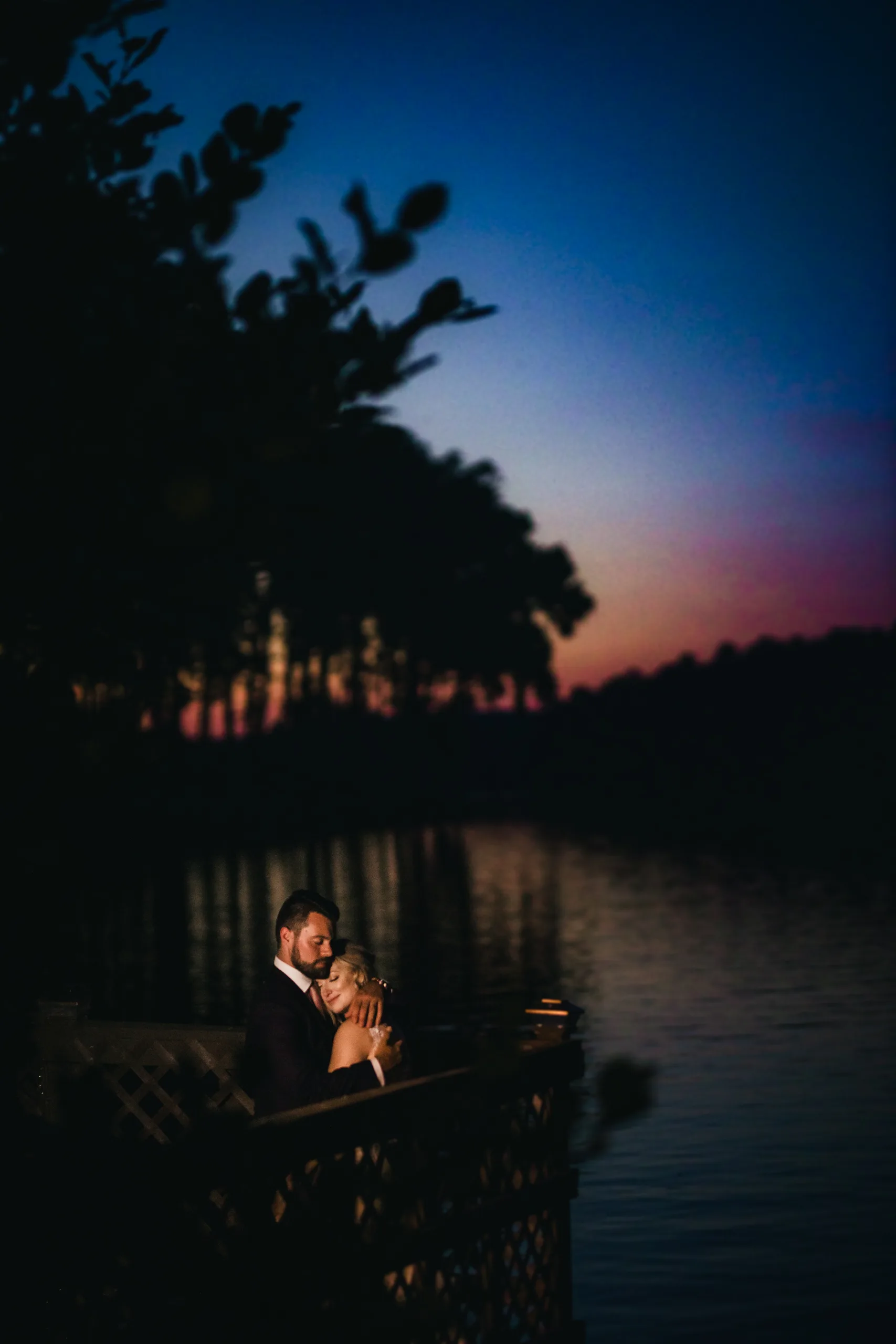Wedding Formals: an embrace by the lake at sunset, at their wedding at Atlanta Evergreen Lakeside Resort in Stone Mountain, GA
